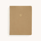 Simplifieds Leatherette Journal - Fawn has a minimalist design with gold foil details and a small, gold-embossed emblem on the cover. This elegant notebook is presented closed against a light background.