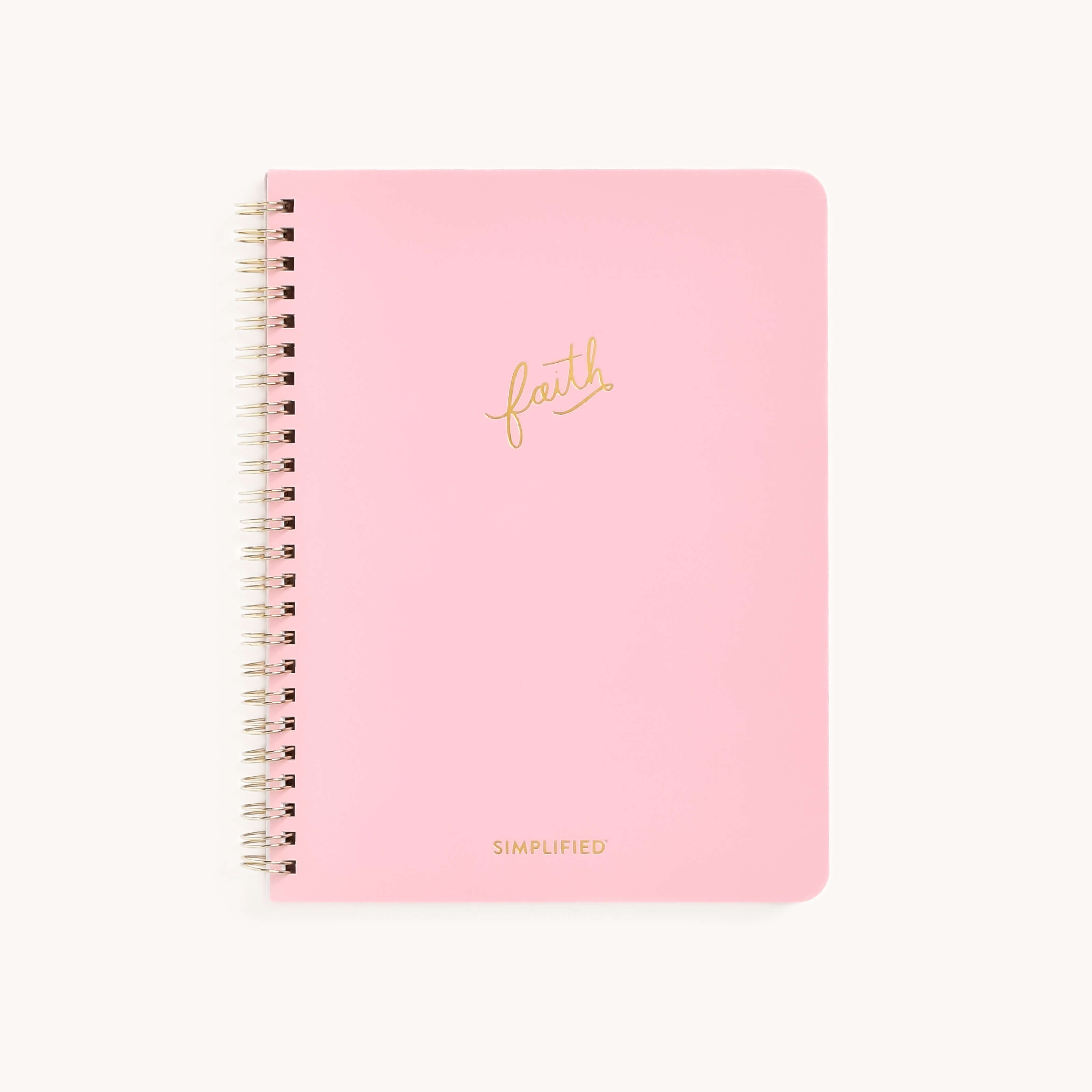 The Workbook - Faith by Simplified is a pink spiral-bound notebook featuring faith in gold script and SIMPLIFIED in gold at the bottom. Its off-white background inspires growth—ideal for mapping actionable plans and goals.