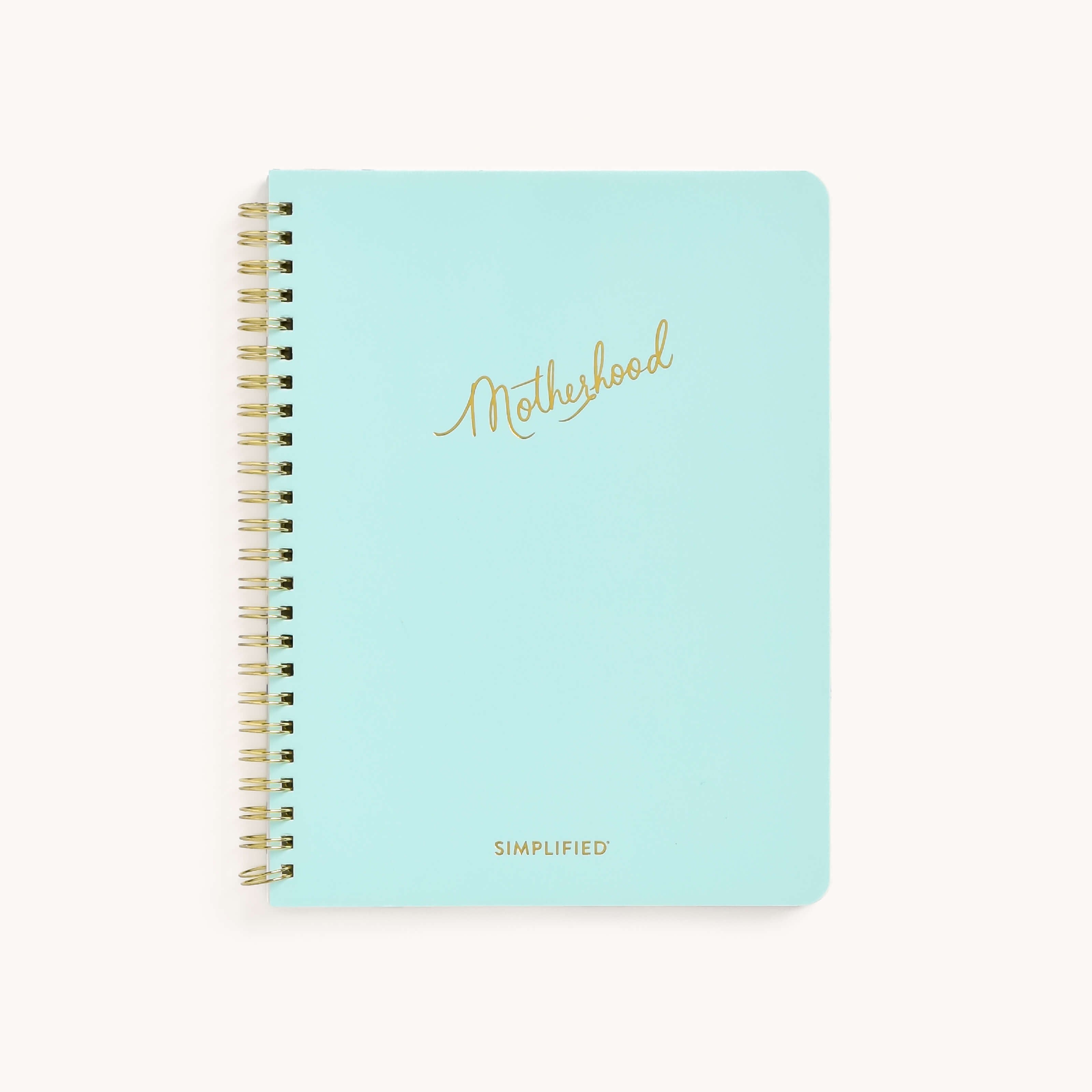 The Workbook - New Motherhood by Simplified is a spiral-bound notebook with a light blue cover and rounded corners. Motherhood is elegantly scripted in gold, while SIMPLIFIED appears at the bottom, making it perfect for busy parents to organize thoughts—a true moms workbook.