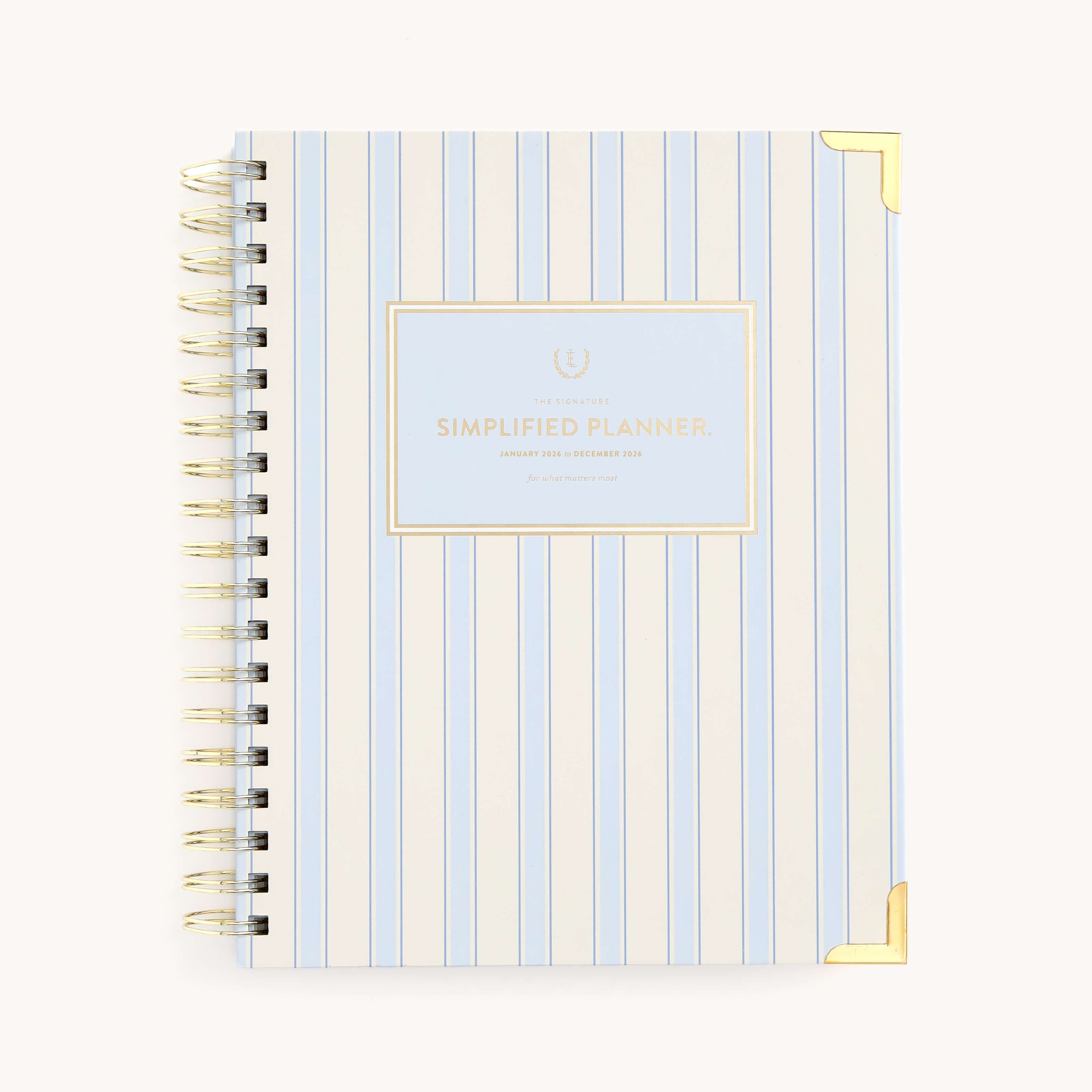 The 2026 Spiral Weekly Simplified Planner - Serene Stripe by Simplified features a light blue and white vertical stripe cover, gold metal corners, and a gold Simplified Planner label—a stylish and functional 12-month planner.