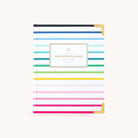 The 2025-2026 Bookbound Weekly Simplified Planner - Happy Stripe by Simplified boasts a stylish white cover adorned with horizontal pink, blue, green, and yellow stripes, gold foil corners, and a central label reading Simplified Planner, making it an elegant organizational tool.