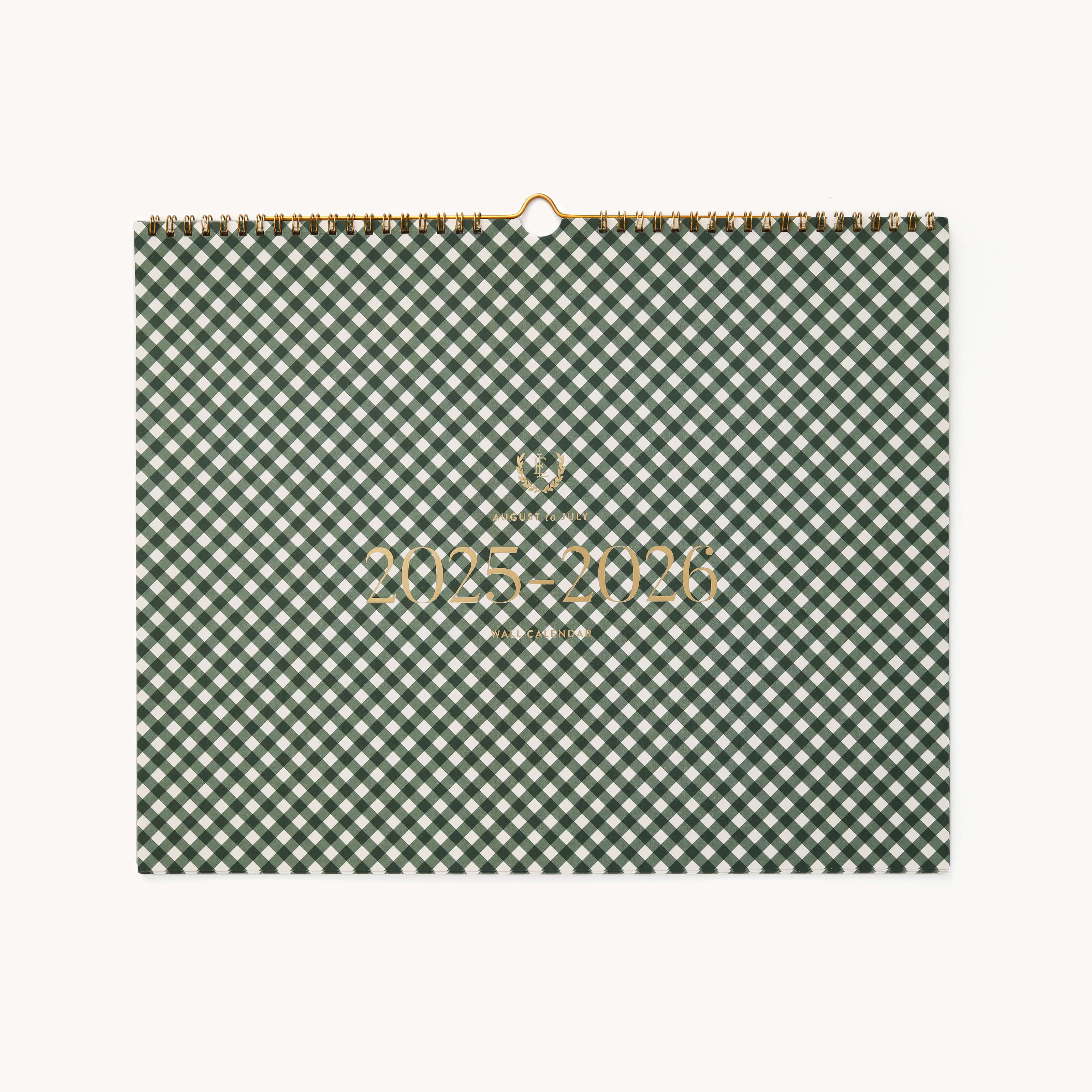 The Simplified 2025-2026 Wall Calendar has a green and white gingham cover with gold lettering, featuring a small logo above. Its bound at the top with a metal ring for hanging.