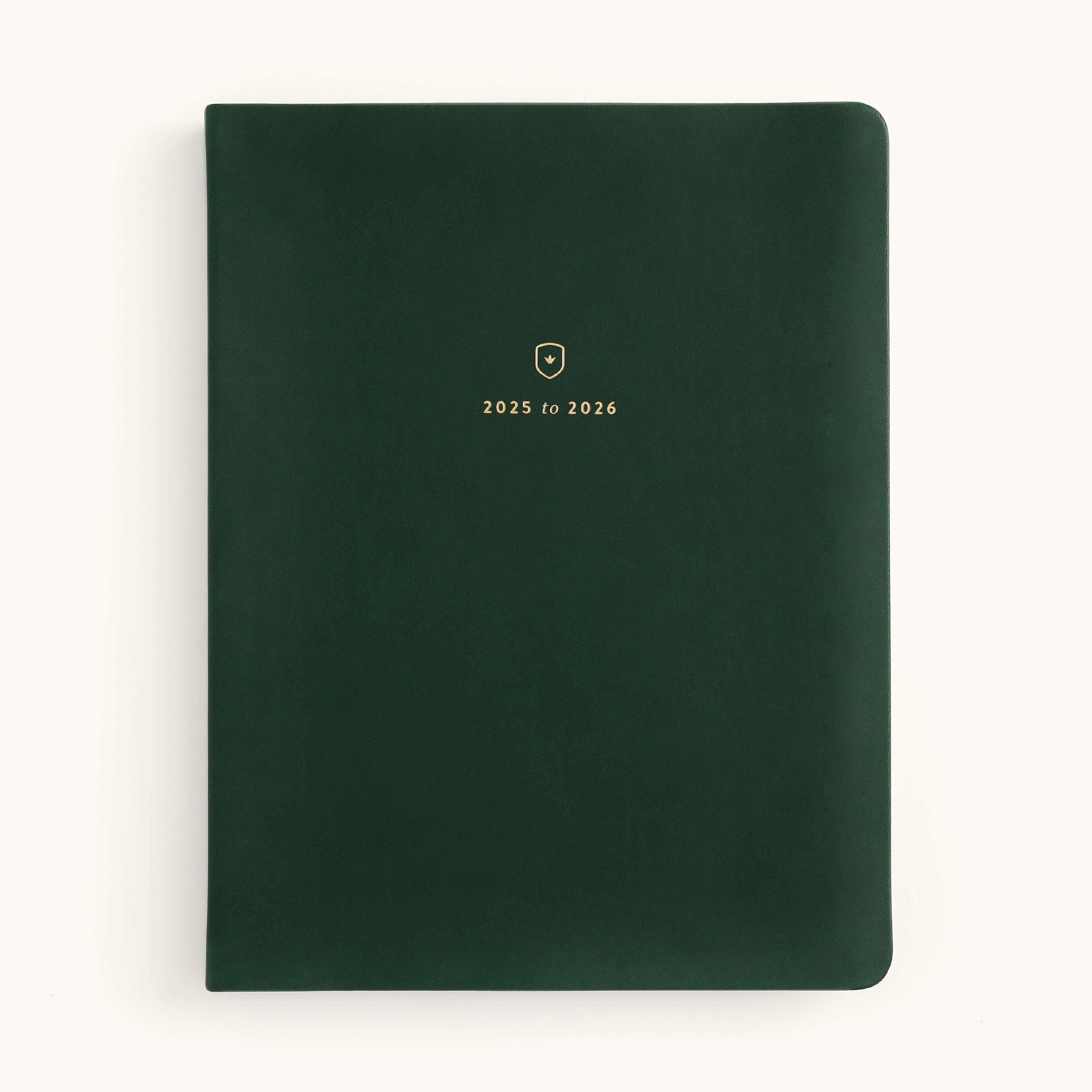 The 2025-2026 Bookbound Weekly Dapperdesk Planner - Evergreen by Simplified features a dark green leatherette cover with rounded corners, 2025 to 2026 gold lettering, and a small gold emblem on the front. It offers a minimalistic design in its 12-month edition.