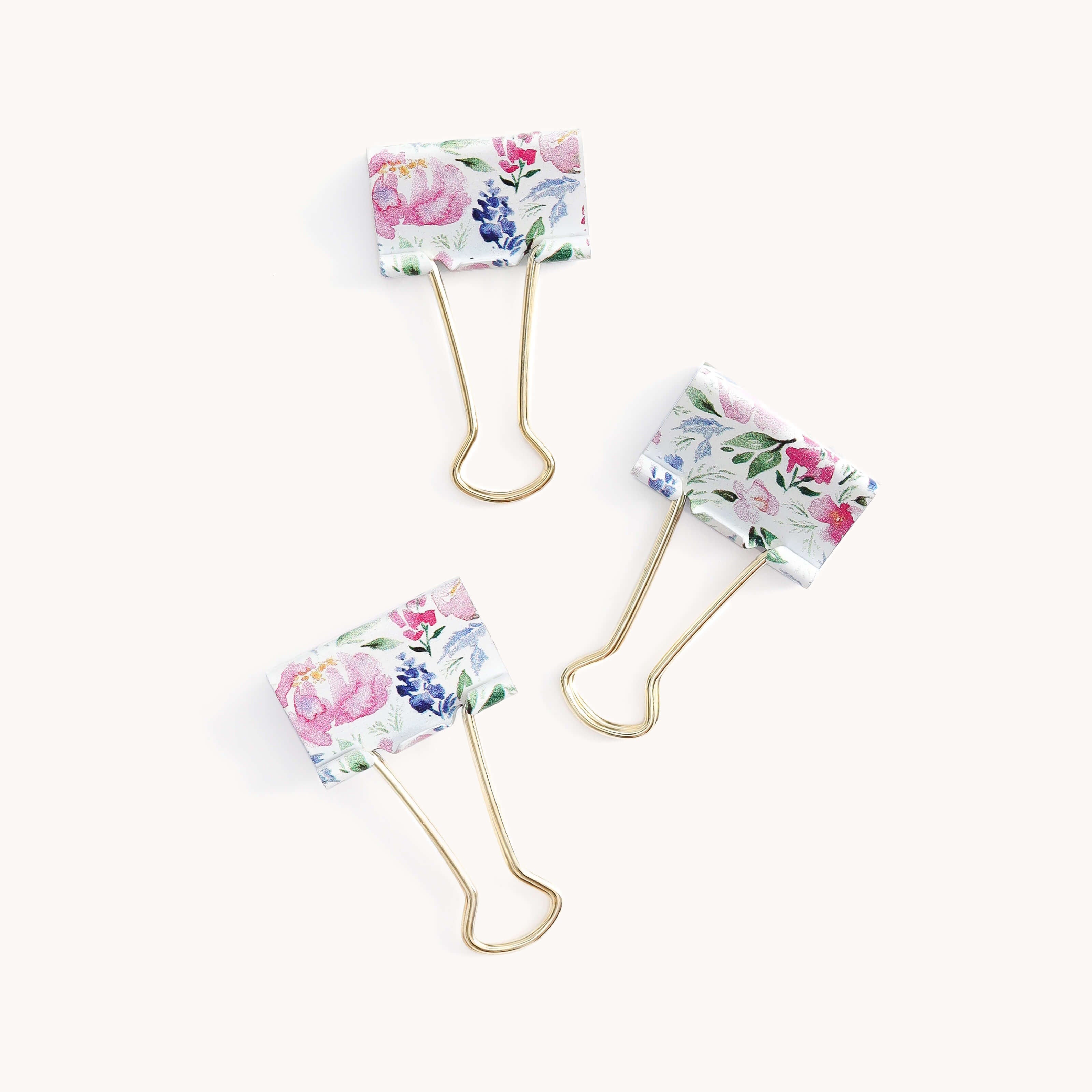 The Simplified Binder Clips - Cottage Floral set includes three stylish gold clips with durable metal construction and clamps featuring floral patterns in pink, blue, and green on a white background.