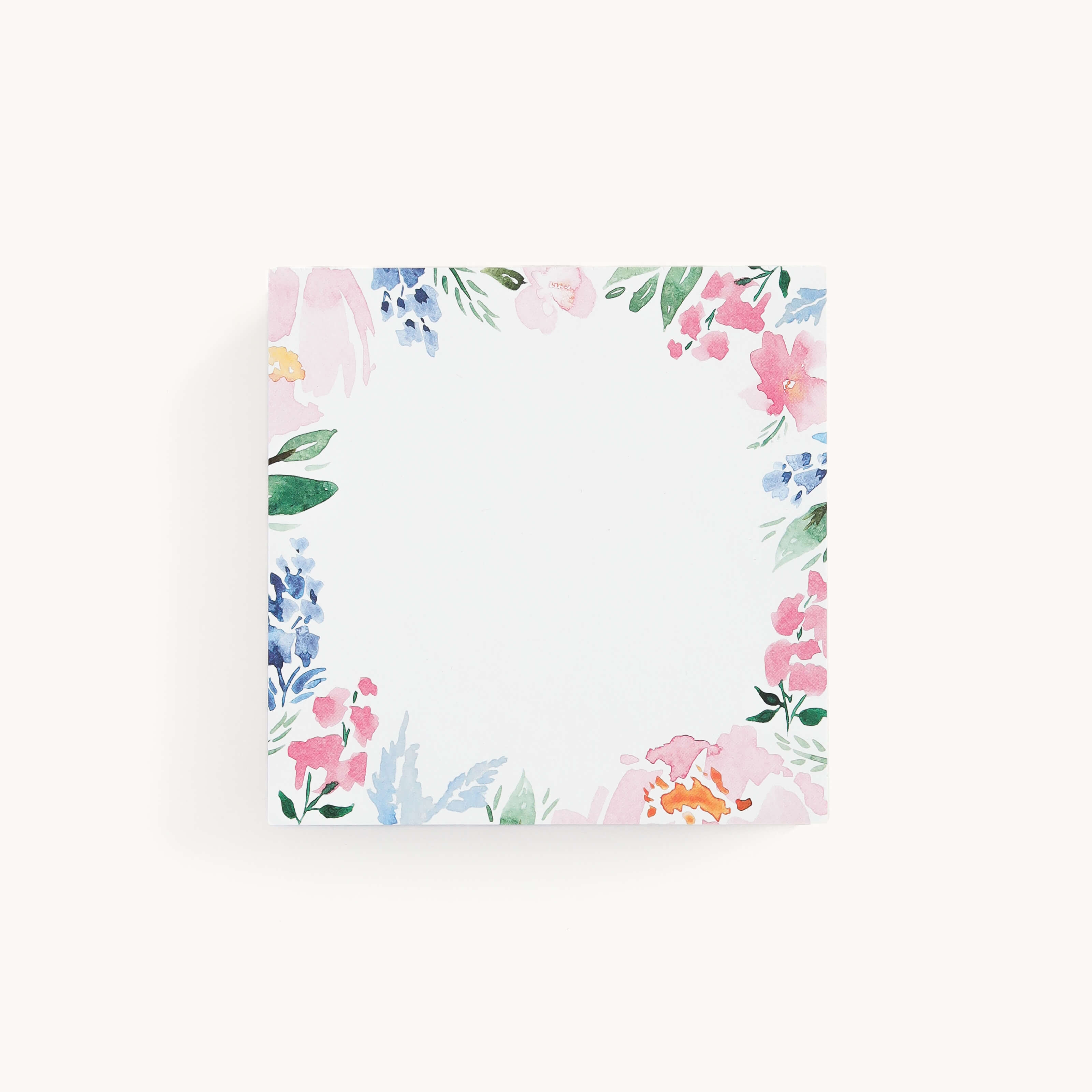The Square Notepad - Cottage Floral by Simplified makes an ideal gift, featuring a watercolor border of pink, blue, and green flowers and leaves on a square design. The off-white center is left blank for notes.