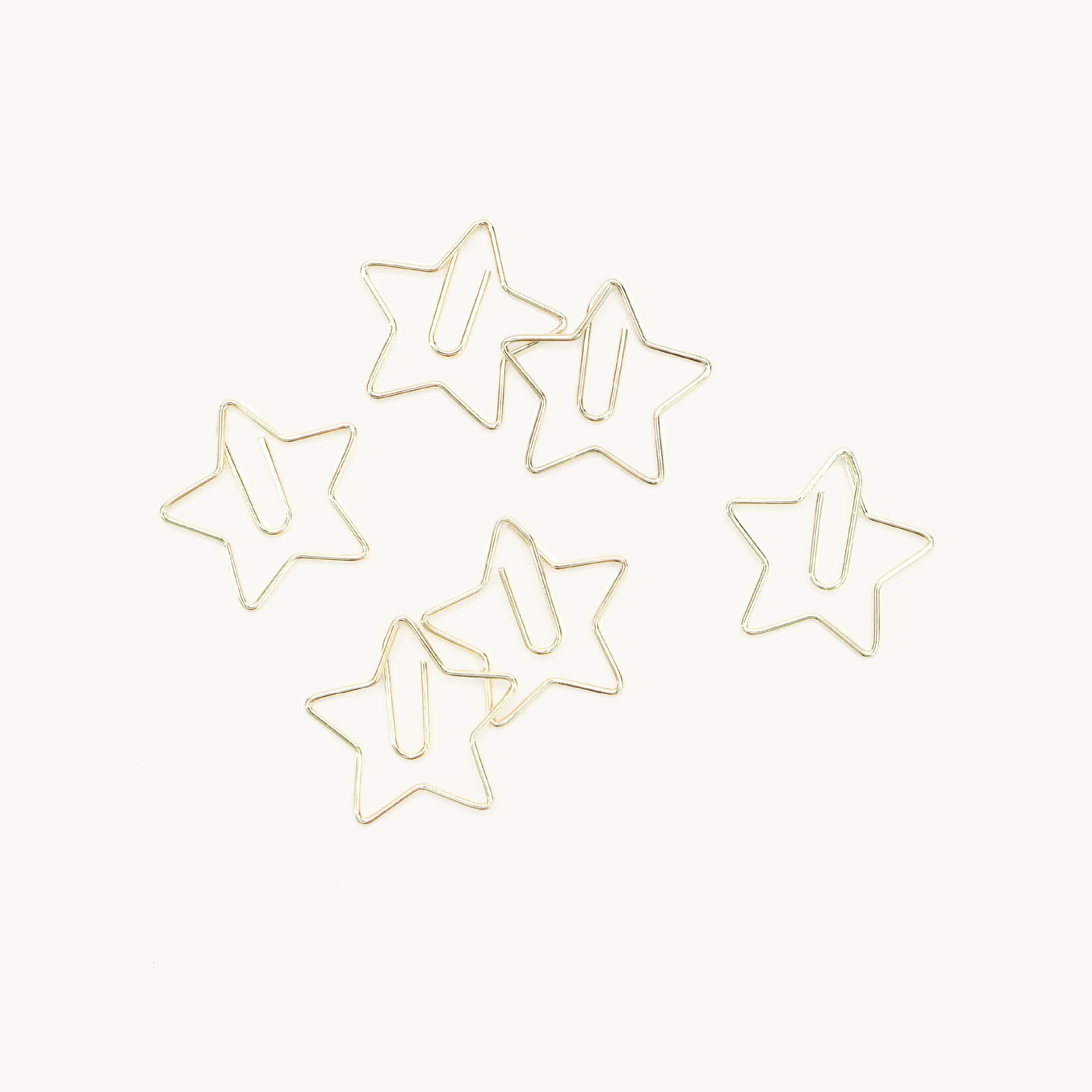 Six gold Simplified® by Emily Ley Paper Clips - Star shaped, neatly arranged on a plain white background.