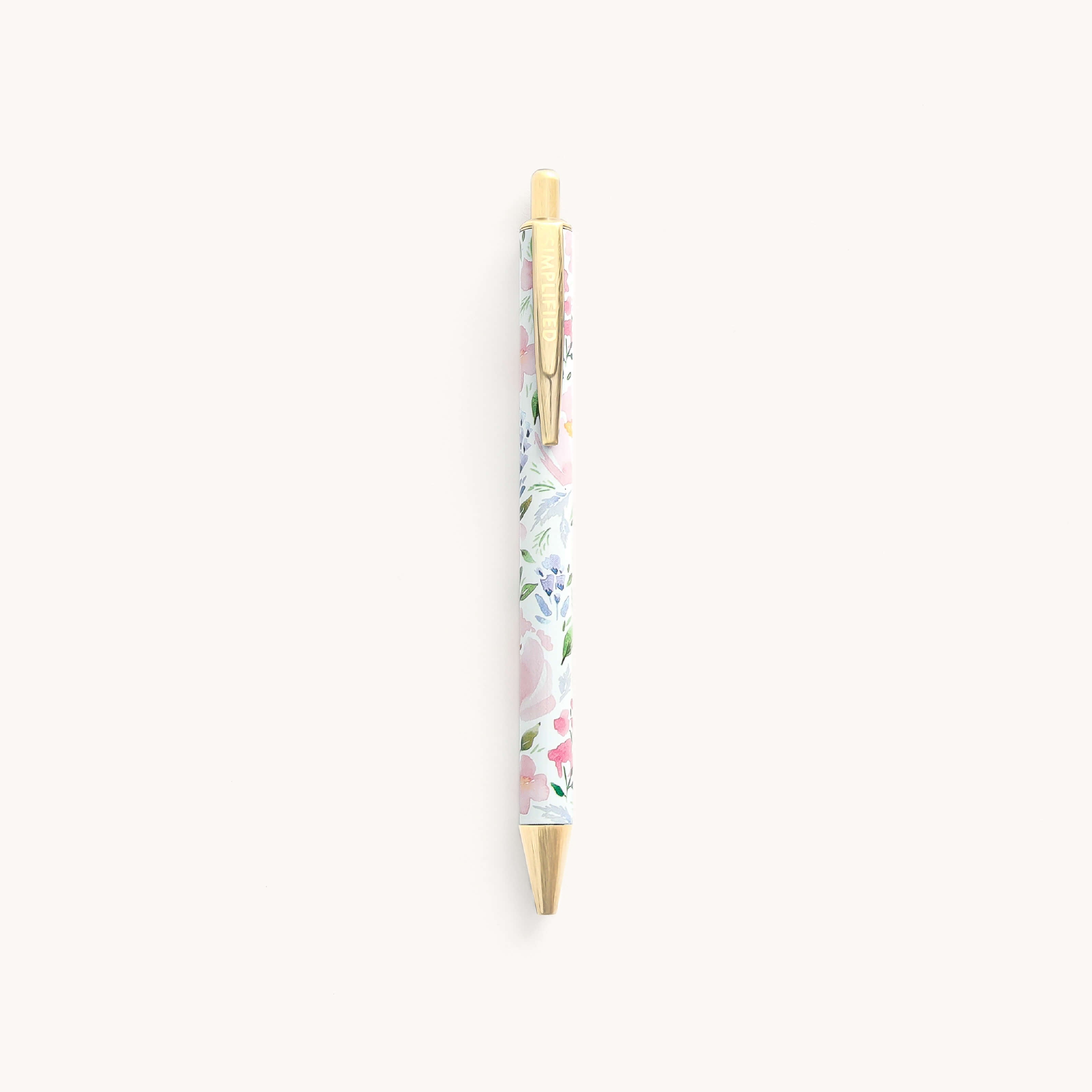 The Click Pen - Cottage Floral by Simplified boasts a refined metal body adorned with a pastel floral design on white, complemented by a gold clip and tip, making it ideal for everyday writing.