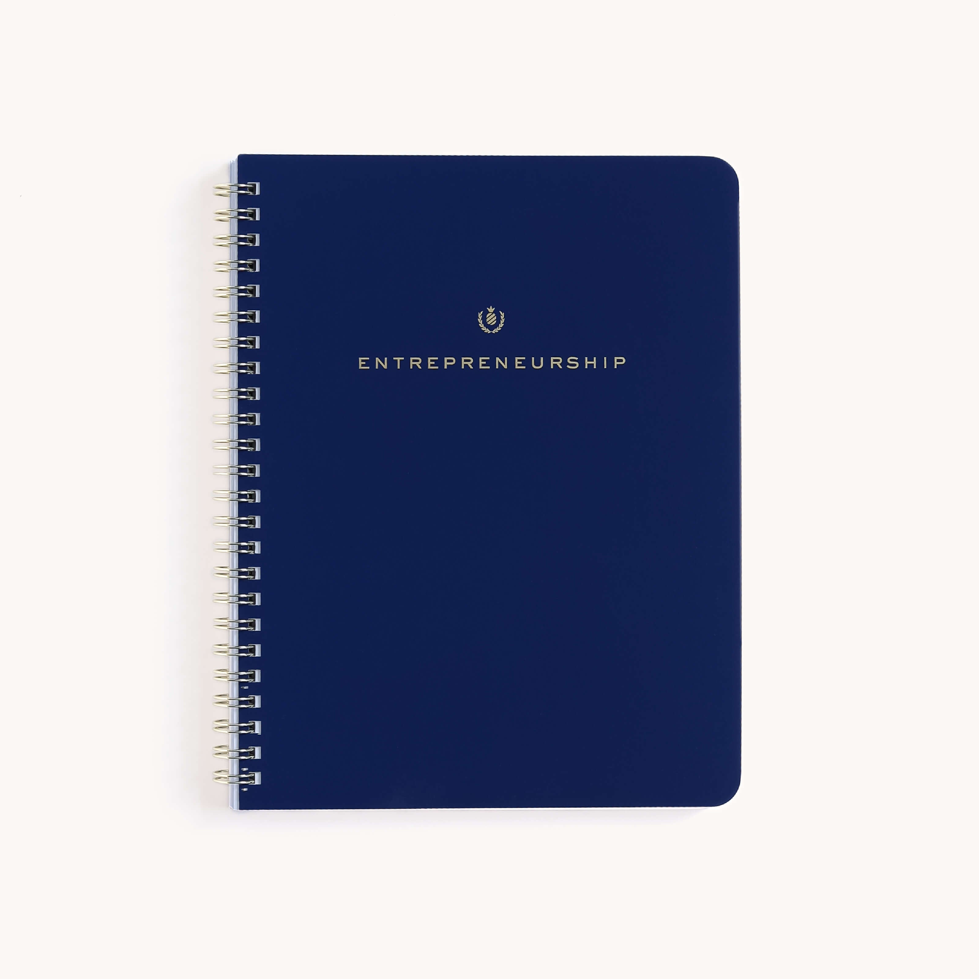 The Simplified Workbook - Entrepreneurship, spiral-bound in dark blue with ENTREPRENEURSHIP embossed in gold on the cover, sits closed and centered against a plain white background, exuding professionalism and ready to capture your business ideas.