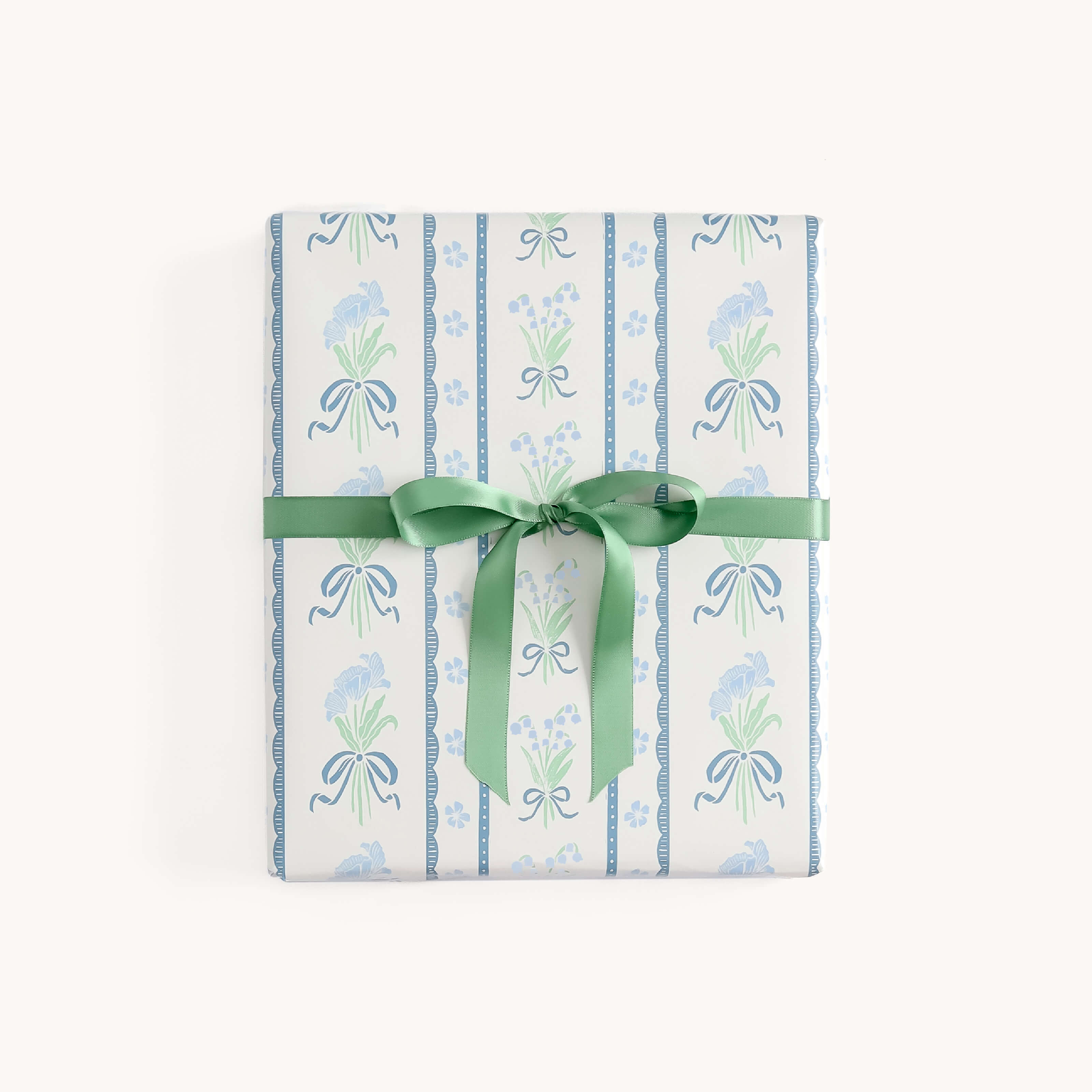 A beautifully wrapped gift box features Simplifieds Gift Wrap Roll - Block Floral, showcasing light blue and green floral patterns and tied with a green ribbon—perfect for holiday gifts.