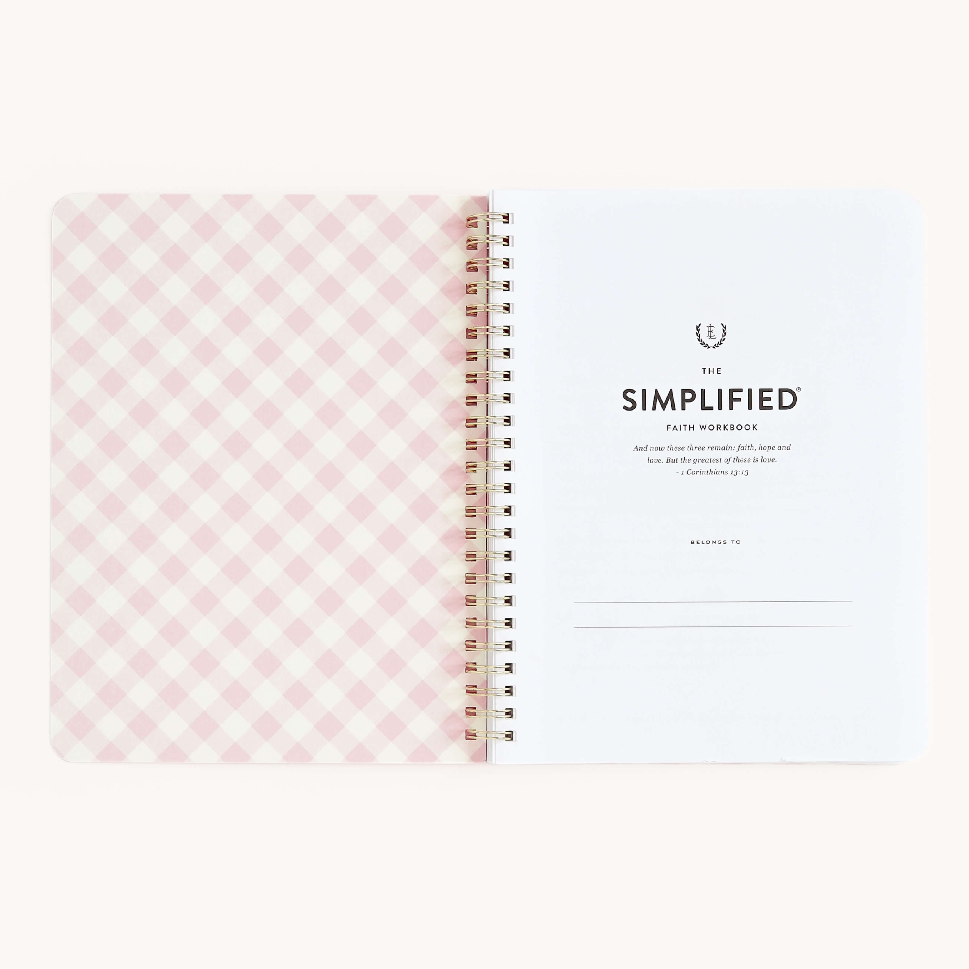 An open spiral-bound Workbook - Faith by Simplified, featuring a pink and white checkered inside cover on the left and a title page on the right with space for a name, designed for goal-setting and making actionable plans.