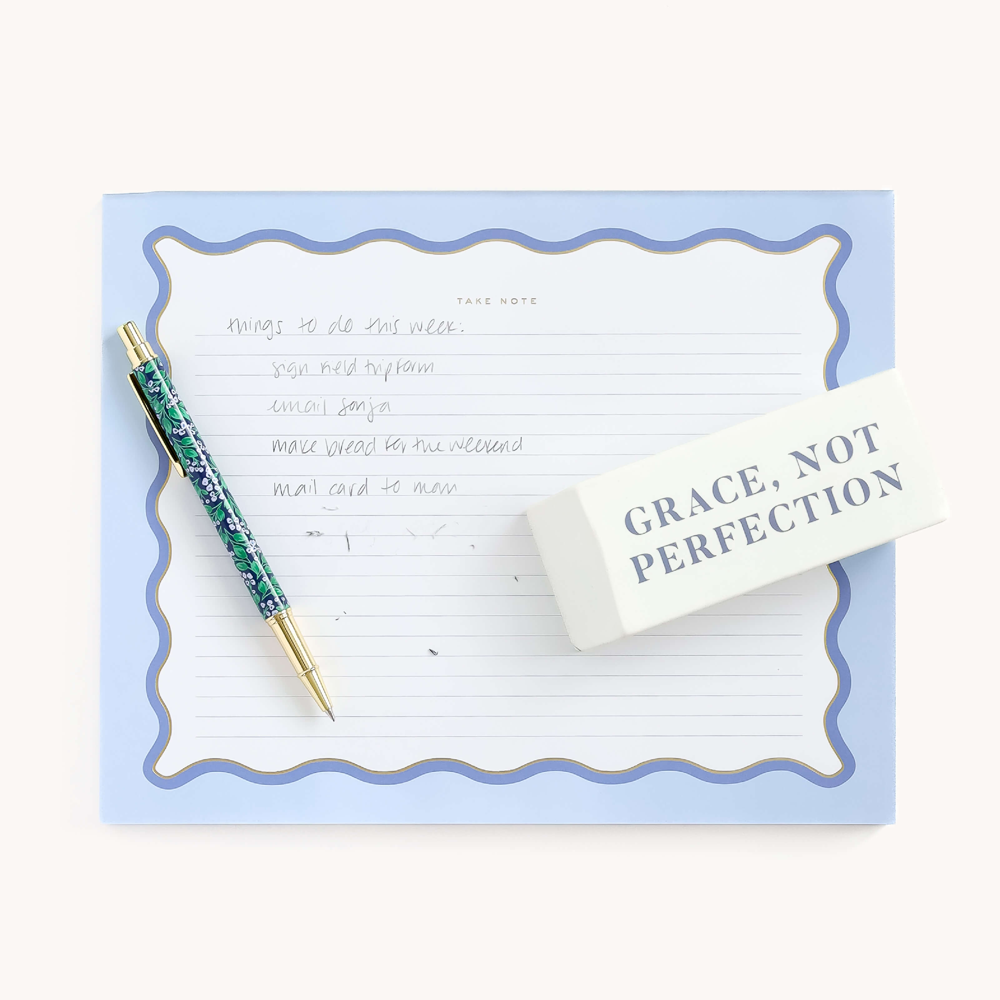 The Simplified Jumbo Eraser - Grace Not Perfection is a lined notepad with a blue border and handwritten tasks, accompanied by a blue and gold pen and featuring the phrase GRACE, NOT PERFECTION, with tasks like make bread and mail card.