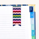 The Page Marker - Rainbow Row by Simplified features a wavy striped bookmark, monthly tabs from August to January in calming blue and green shades on the right edge, and a magnetic page marker for an elegant planner style.