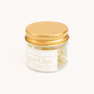 A small glass jar with a gold lid, labeled Paper Clips - Bows by Simplified in an elegant font, contains 12 heavy-duty brass paper clips, ideally formed for any task, set against a plain light background.
