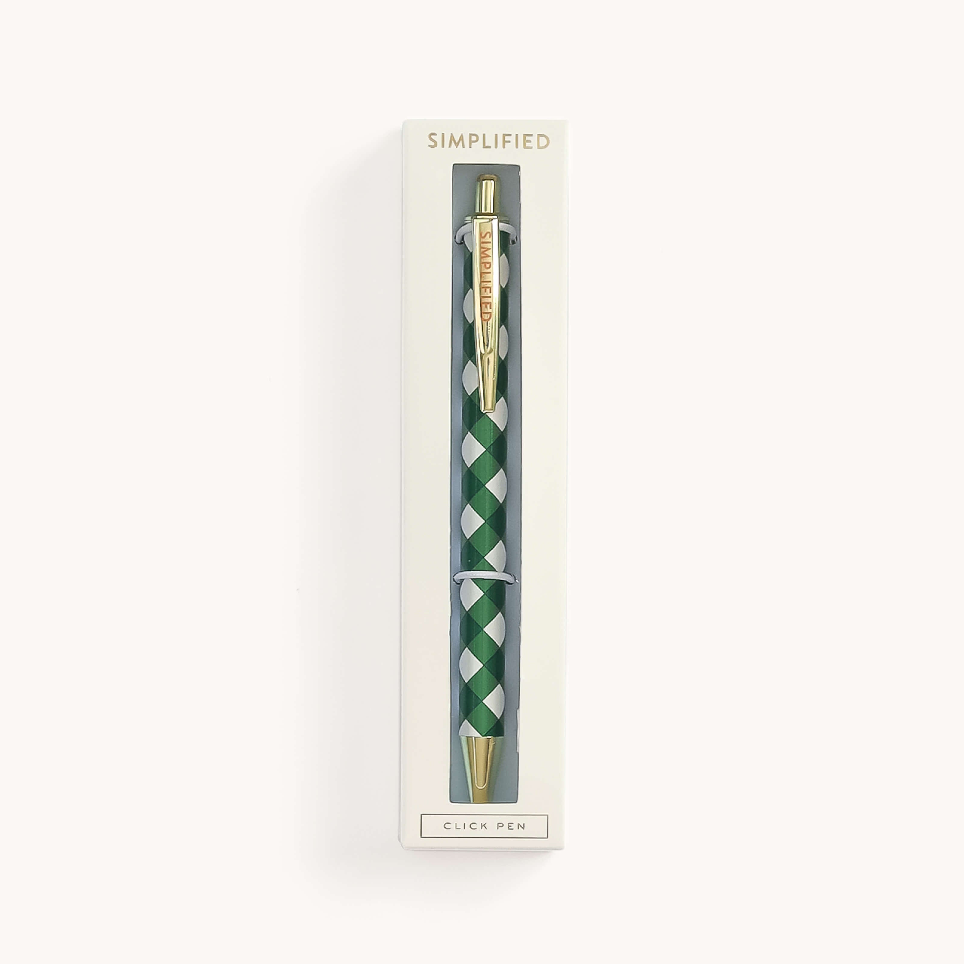 The SIMPLIFIED Click Pen - Camp Gingham features a green and white checkered design with gold accents and a retractable top. Its elegantly positioned vertically in a cream rectangular box labeled SIMPLIFIED with CLICK PEN at the bottom.