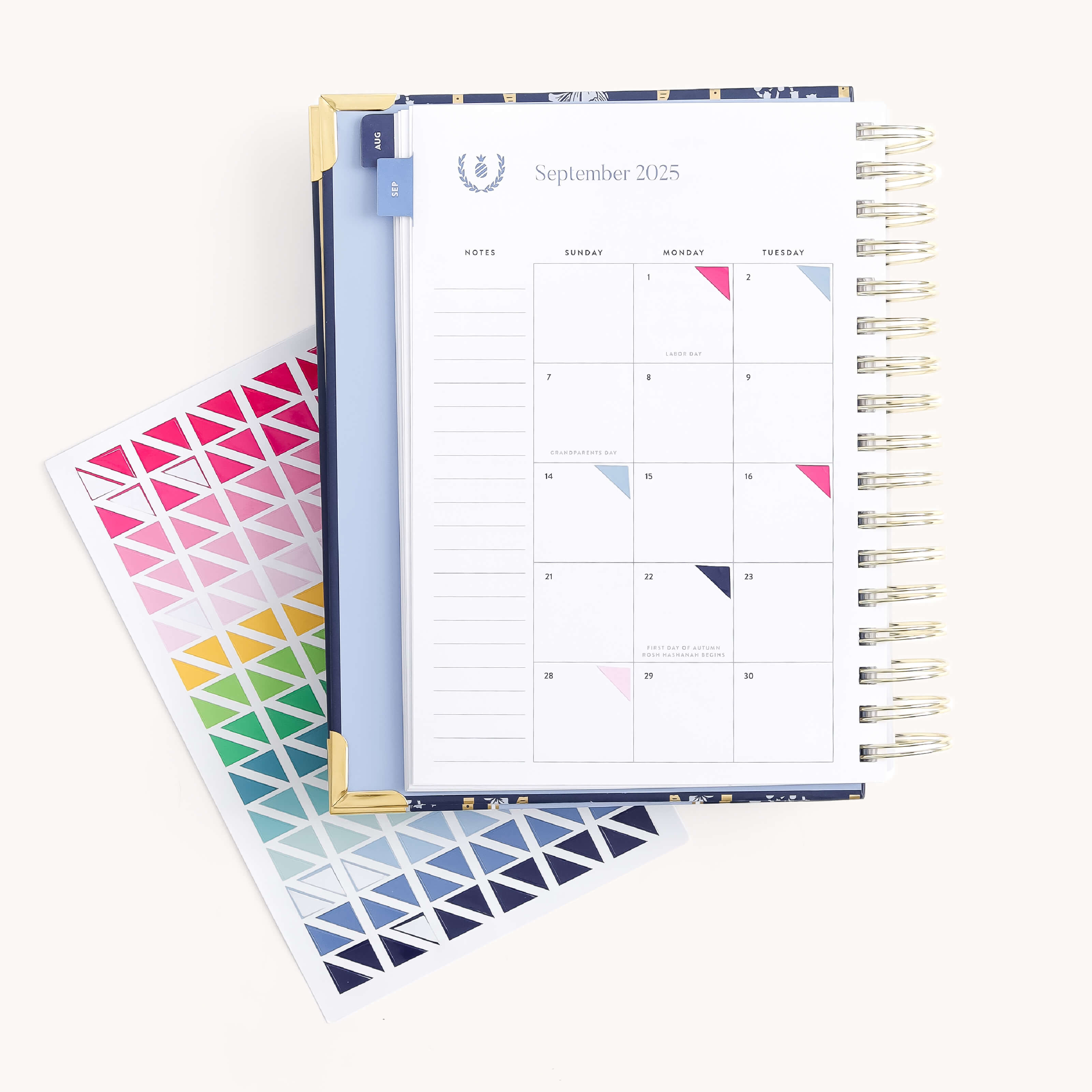An open spiral-bound planner shows a September 2025 monthly calendar. Beside it is the Simplified Sticker Set - Triangle Corners, featuring vibrant pink, blue, green, yellow, and purple stickers—ideal for color-coding your planner.