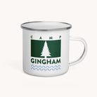The Simplified Enamel Mug - Camp Gingham features a green rectangle with a white pine tree, CAMP GINGHAM text, and blue waves. Lightweight and durable, it’s perfect for summer camp adventures.