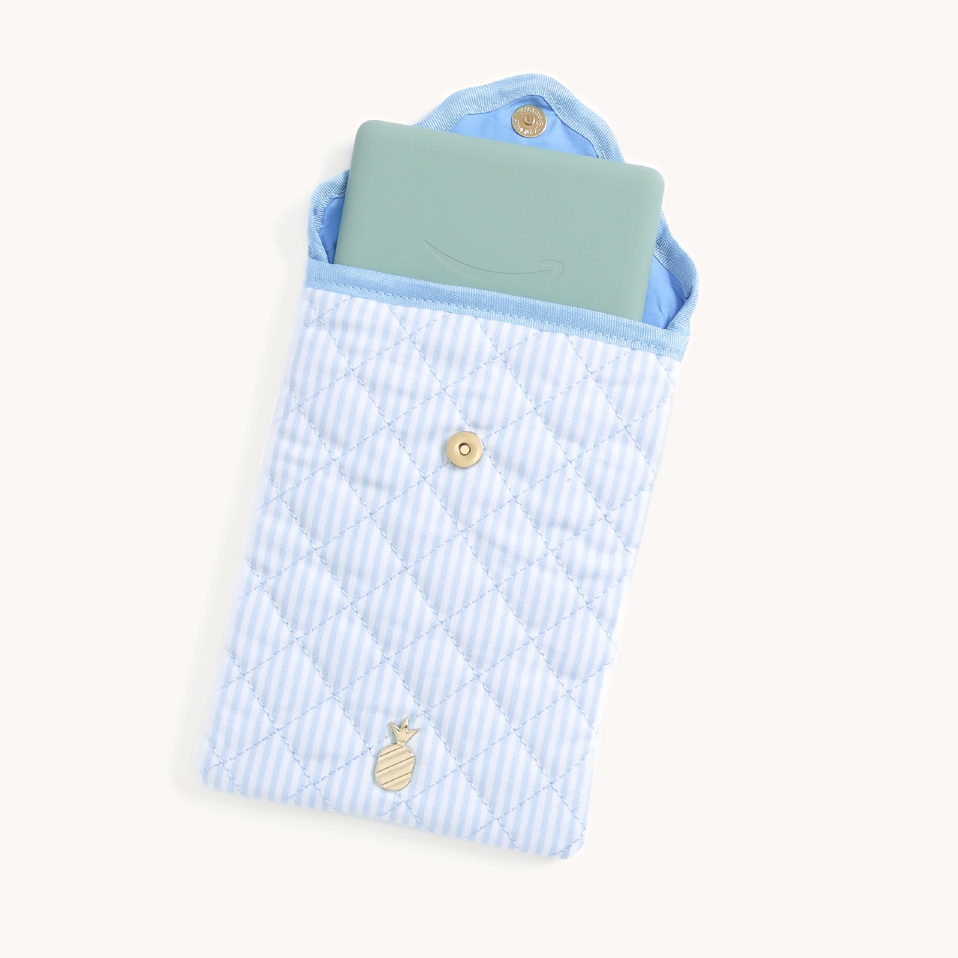 Light blue Blue Pinstripe Quilted E-Reader Case with an e-reader inside with a gold pineapple charm on a white background