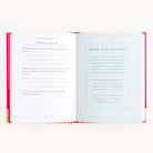 Place the Grace Not Perfection book by Simplified on a flat surface. The left page, Tips for Letting Go, has fill-in-the-blanks and life-guiding questions. The right, titled Grace With Yourself, includes text on self-love and embracing imperfection in cursive and regular fonts on white.