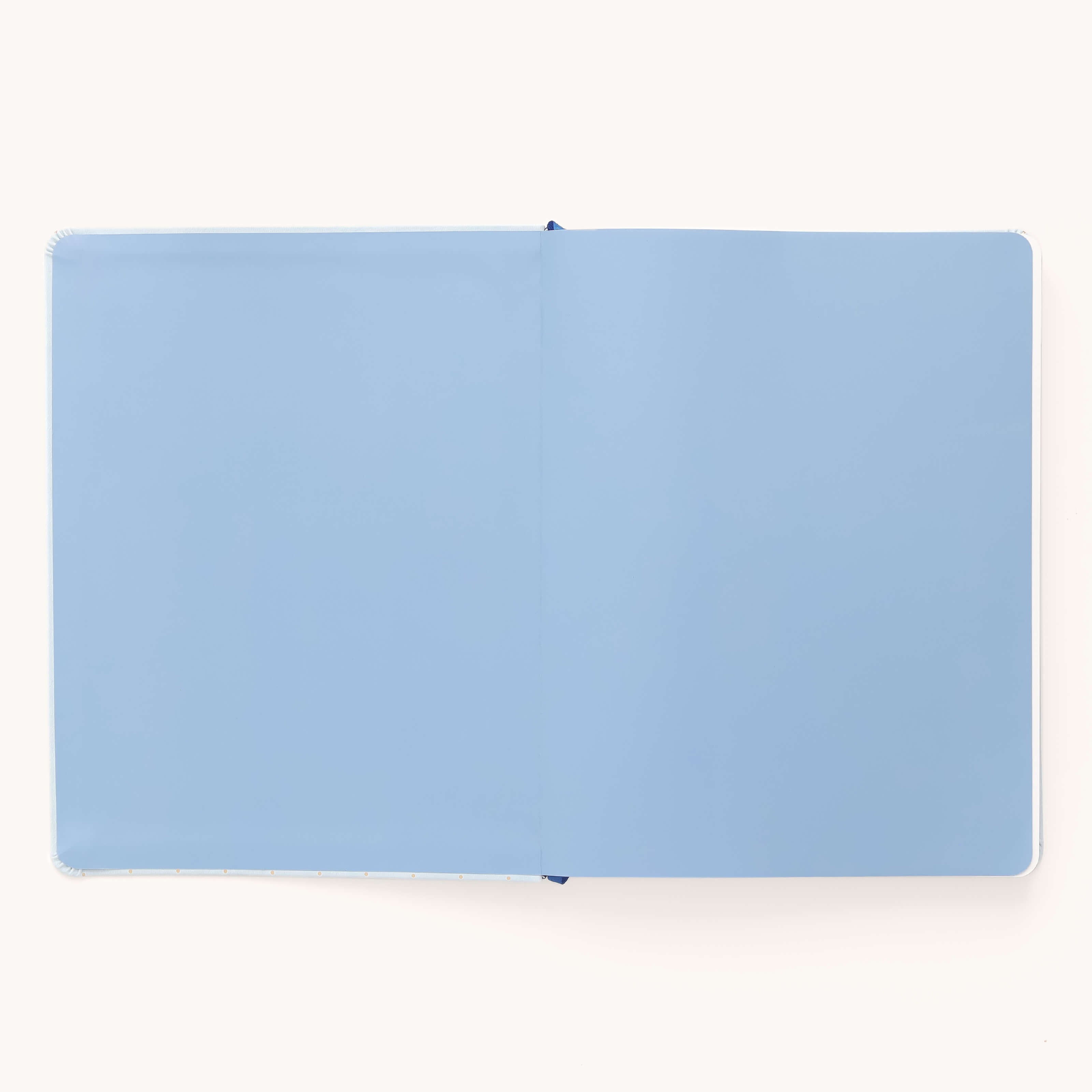 The Simplified 2026 Bookbound Weekly Dapperdesk Planner in Carolina Dot features a sleek leatherette cover and opens flat to reveal light blue, completely blank pages.