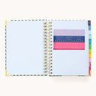 The 2025-2026 Spiral Daily Simplified Planner - Camp Gingham by Simplified features blank white pages with gold foil accents on the corners, colorful tab dividers on the right, and colored stencils with letters and numbers on the left, making it perfect for your prep work.