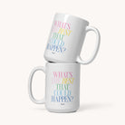 Two 15 oz Simplified "Mug - Best That Could Happen" ceramic mugs stacked, each with “WHAT’S THE BEST THAT COULD HAPPEN?” in pastel pink, yellow, green & blue. Microwave and dishwasher safe. Plain background.