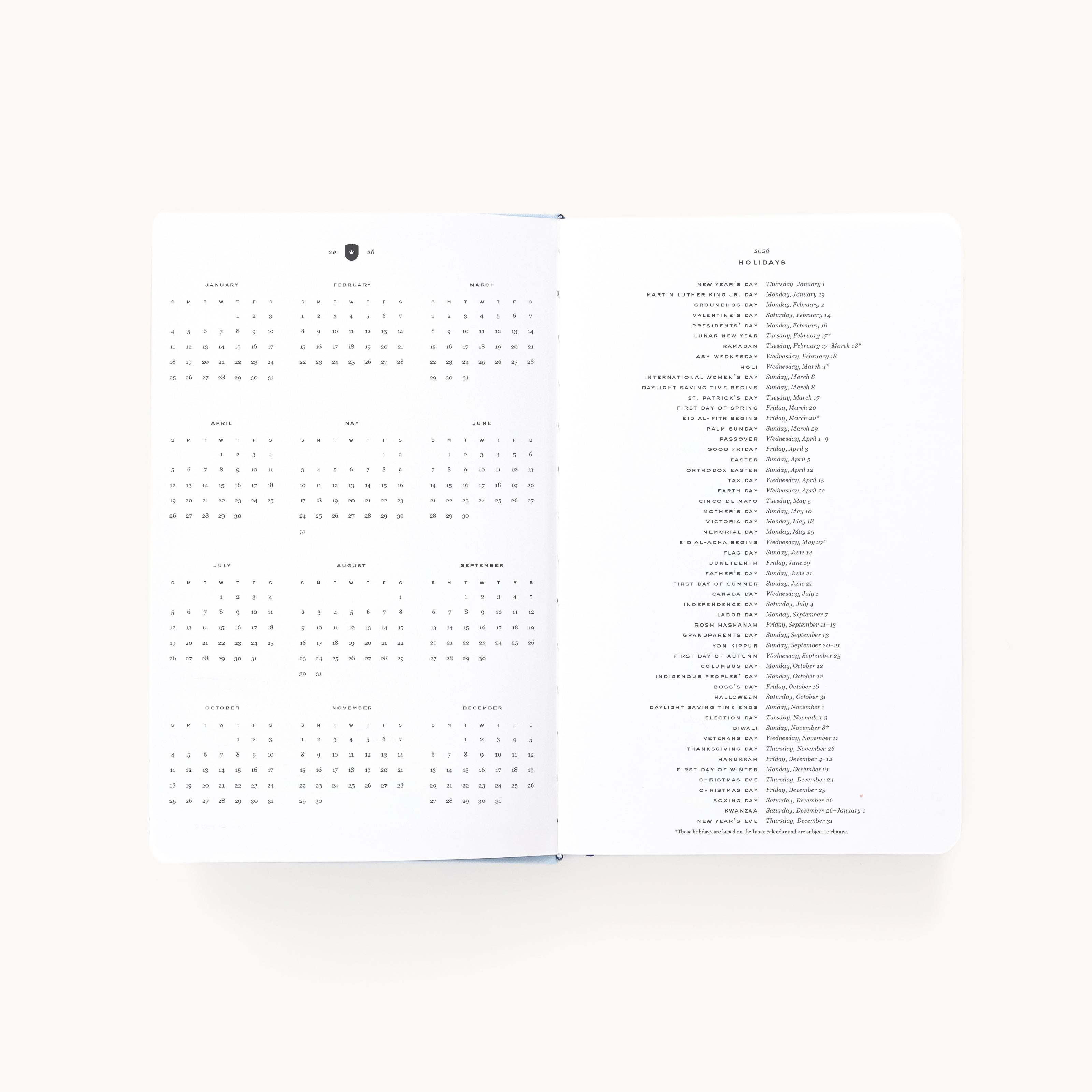 The 2026 Bookbound Daily Dapperdesk Planner - Carolina Dot by Simplified features a 12-month spread with a yearly calendar on the left and holidays and observances listed by date on the right, all in small black text on crisp white paper.