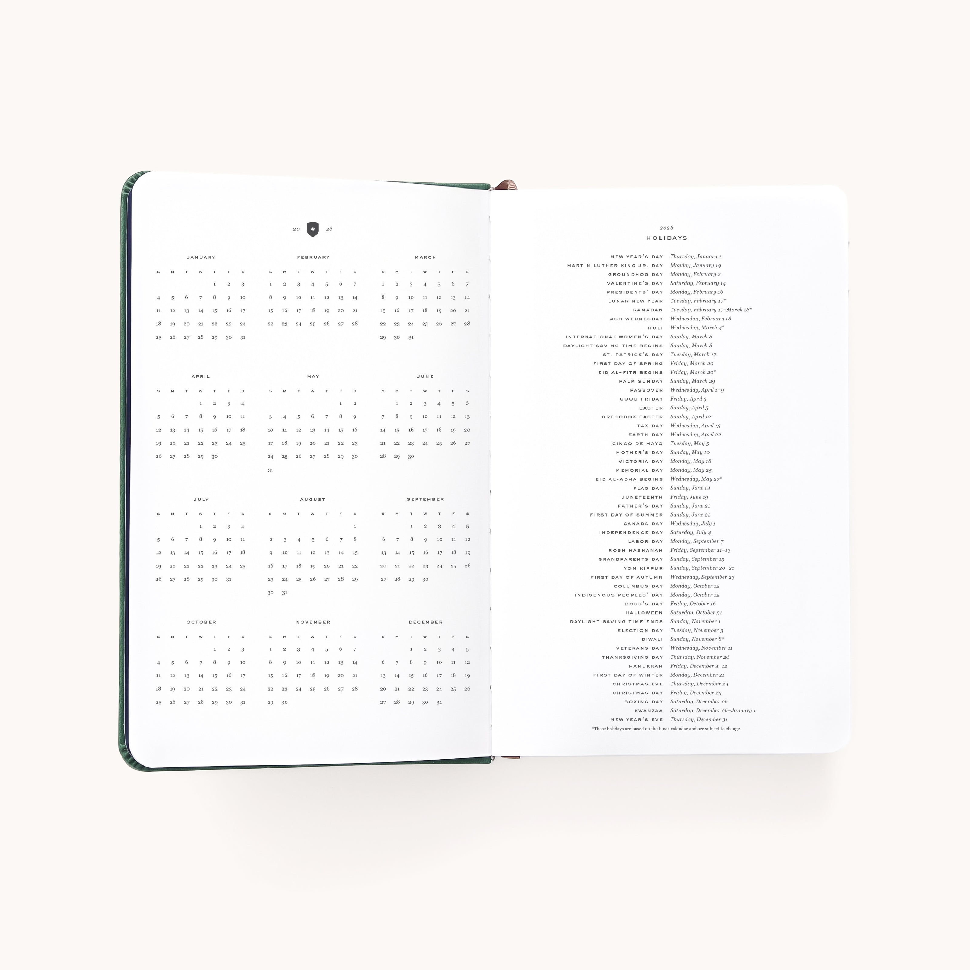 The Simplified 2026 Bookbound Daily Dapperdesk Planner - Evergreen shows a year calendar on the left and holidays with dates on the right, featuring a light background and a chic leatherette cover.