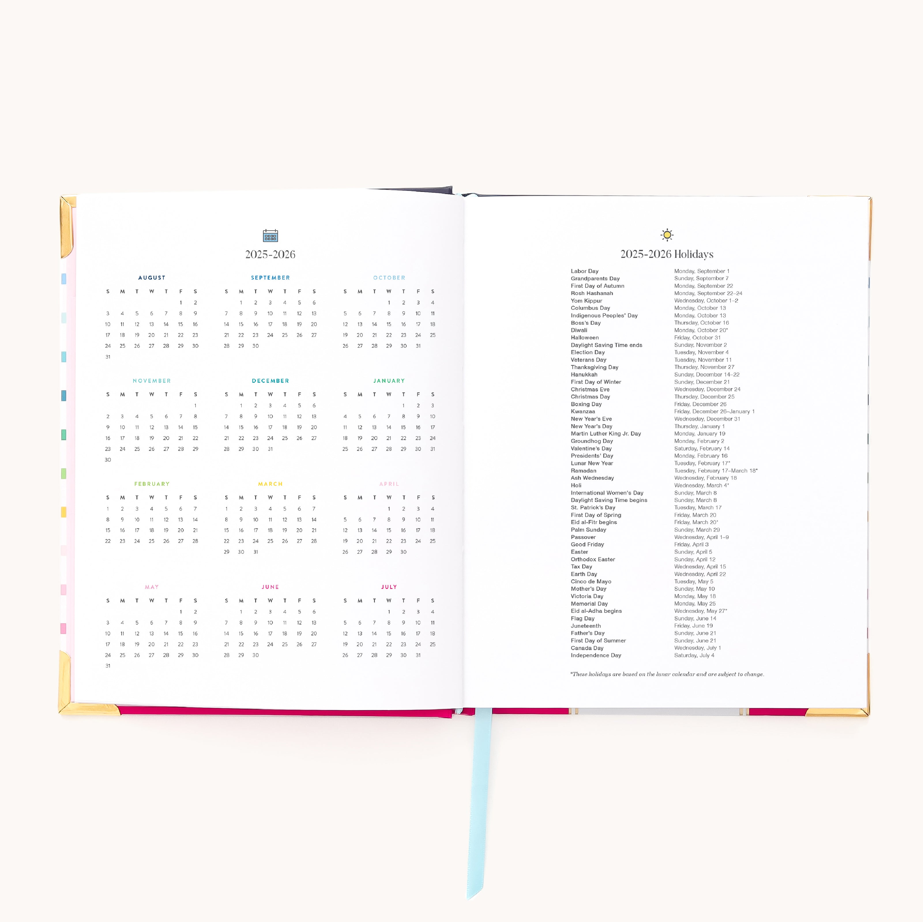 The 2025-2026 Bookbound Weekly Simplified Planner by Simplified opens to reveal a calendar on the left and a holiday list on the right. A light blue ribbon bookmark is centered, with subtle gold foil edging. The plain white background enhances its minimalist elegance.