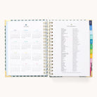 The Simplified 2025-2026 Spiral Daily Planner - Camp Gingham showcases refined gold foil accents with an open layout; calendars for 2025 and 2026 on one side, holidays on the other. Its spiral binding and colorful tabs ensure easy organization.