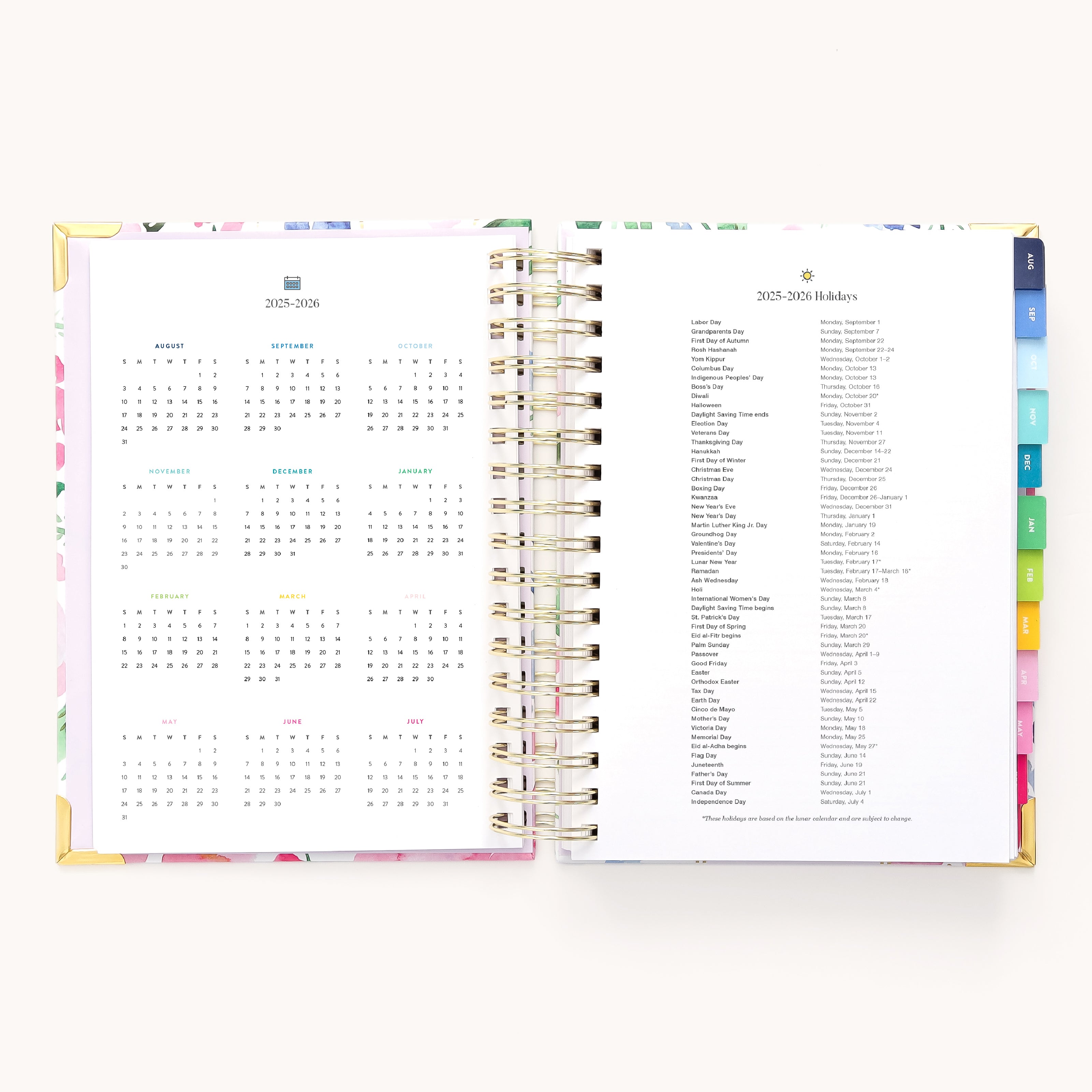 The 2025-2026 Spiral Daily Simplified Planner - Cottage Floral by Simplified opens to reveal a 2023-2025 calendar on the left and a holiday list on the right, both enhanced with elegant gold foil. It features spiral binding and vibrant tabbed sections for easy organization.