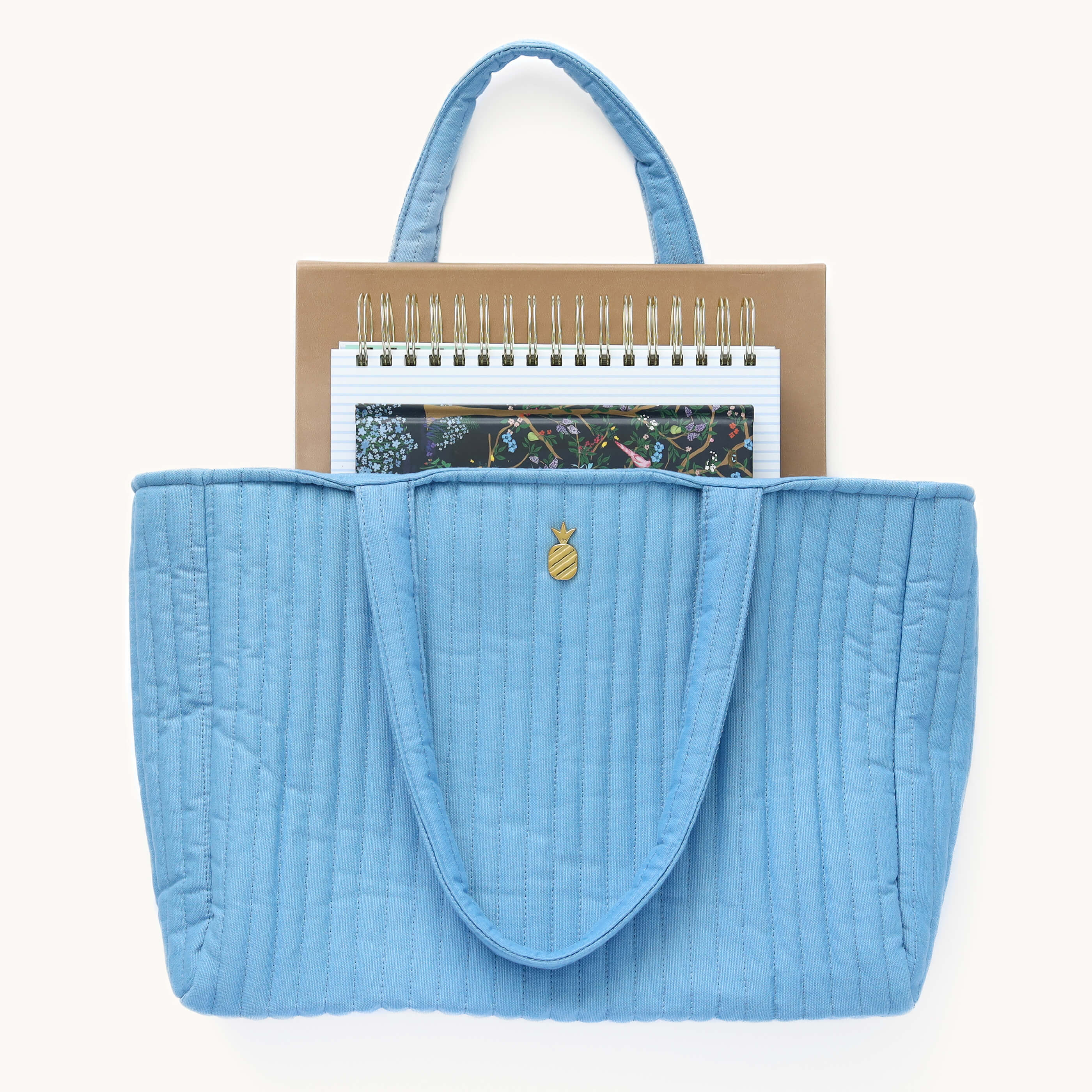 A Weekly Simplified Planner, Daily Simplified Planner, and Weekly Dapperdesk Planner peeking out of a Quilted Tote Bag in French Blue.