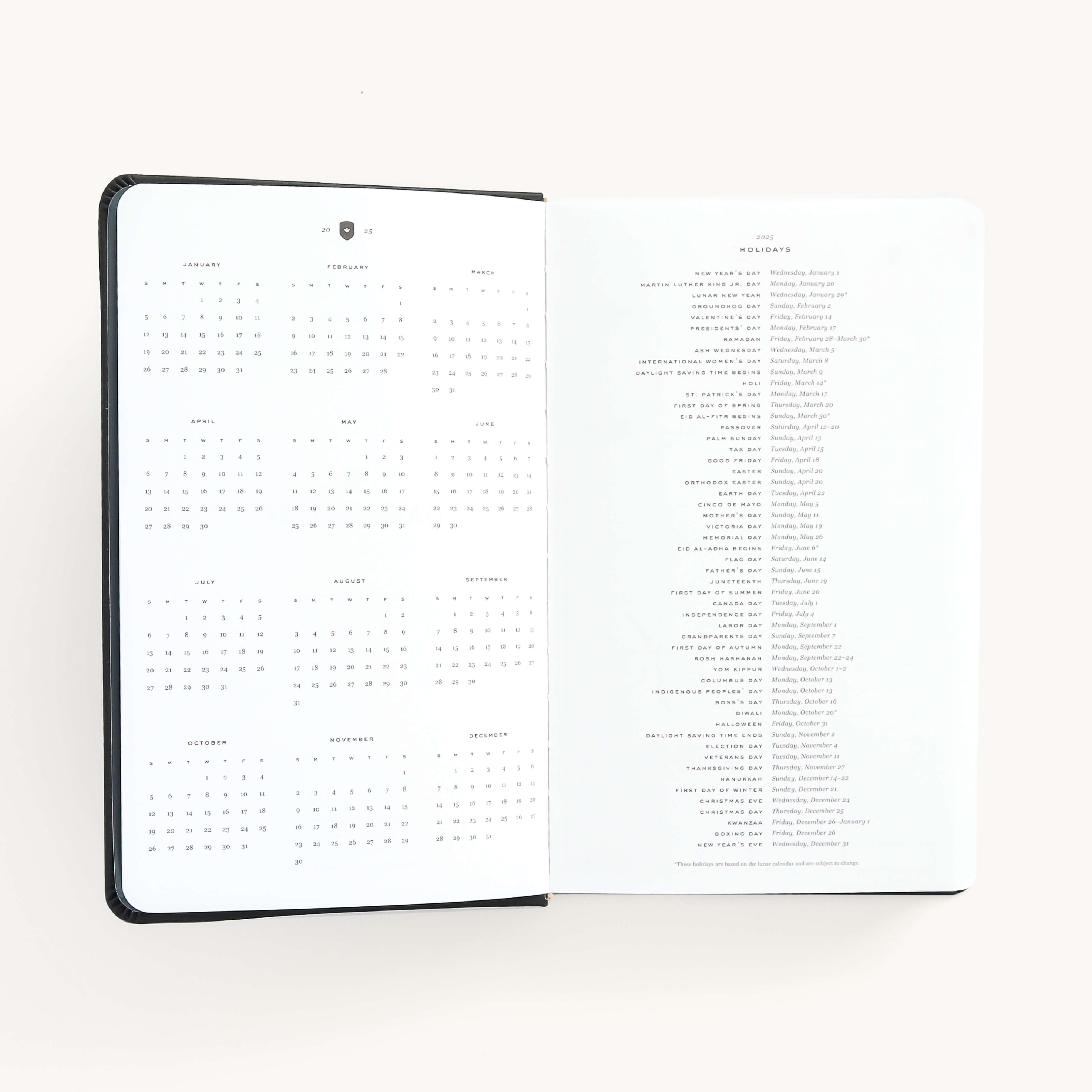 2025 Daily Dapperdesk Planner by Emily Ley in the Black Tie leatherette cover open to the yearly calendar overview and holidays list. Features a two-page spread with a full 12-month calendar view on the left and important U.S. holidays on the right.