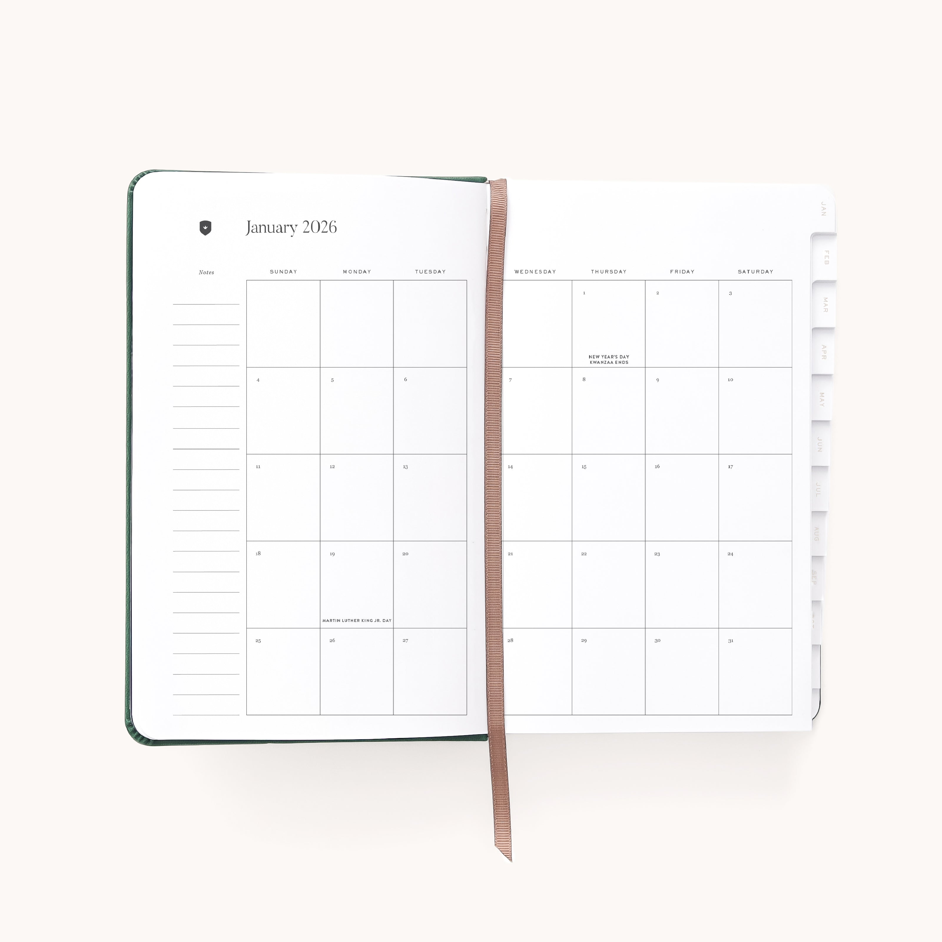 The 2026 Bookbound Daily Dapperdesk Planner - Evergreen by Simplified lies open, showing January’s monthly calendar on its leatherette cover pages with a brown ribbon bookmark and visible side tabs for other months. Most pages appear blank.