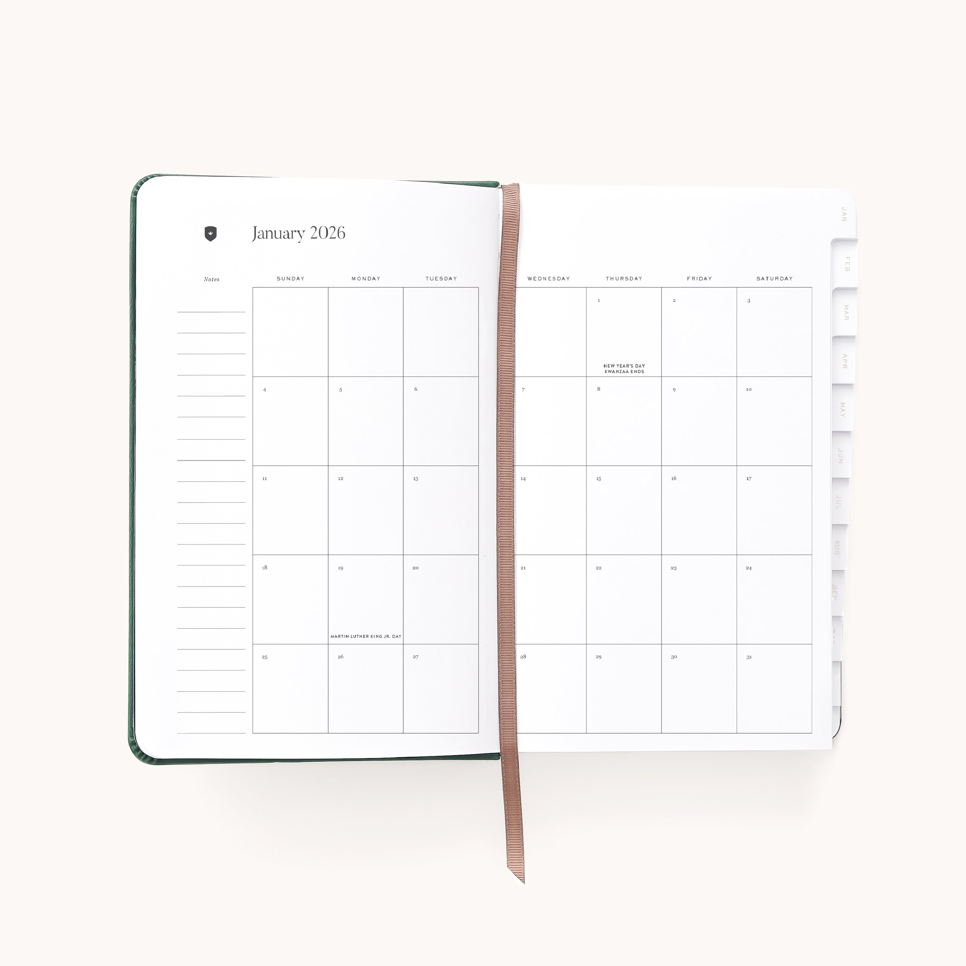 The 2026 Bookbound Daily Dapperdesk Planner - Evergreen by Simplified lies open, showing January’s monthly calendar on its leatherette cover pages with a brown ribbon bookmark and visible side tabs for other months. Most pages appear blank.