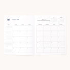 The 2025-2026 Softcover Monthly Simplified Planner - Happy Stripe by Simplified features a calendar for August 2025. It includes a Sunday-to-Saturday grid layout with note spaces on the left page and a small yearly calendar in the top right corner, perfect for seamless planning and organization.