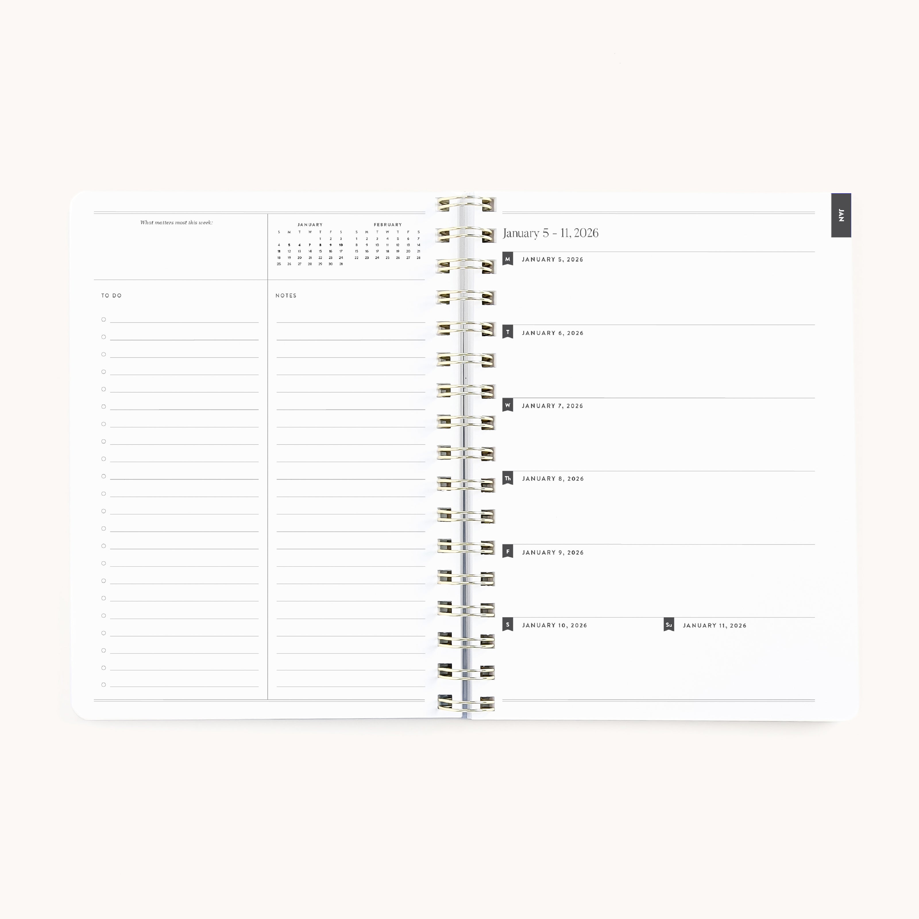 The Simplified 2026 Softcover Weekly Simplified Planner – Ivory Antelope is spiral-bound, opens to a weekly view (Jan 5–11, 2026) with to-do lists and notes on the left, dated daily sections on the right, and a monthly calendar in the upper left corner.