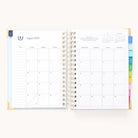 The 2025-2026 Spiral Daily Simplified Planner - Serene Stripe by Simplified features a gold foil detail opening to August 2025 over two pages. The left page has notes sections and a small calendar, while the right offers a large daily grid with dates and a mini next month view at the top.