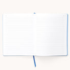The Simplified 2025-2026 Bookbound Weekly Dapperdesk Planner in Carolina Dot, with a leatherette cover, features lined pages and a blue ribbon bookmark, elegantly placed on a light surface.