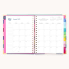 Open the 2025-2026 Spiral Weekly Simplified Planner - Rainbow Row by Simplified to reveal a monthly view for August 2025. The left page has gold foil in the notes, and the right displays Sunday to Saturday days, with organized pages and vibrant color-coded tabs at each months edge.