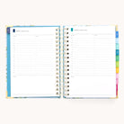 The 2025-2026 Spiral Daily Simplified Planner - Faraway Land by Simplified features an open planner with gold foil, visible spiral binding, and colorful tabs. Pages offer hourly sections from 6 AM to 8 PM and space for notes, encapsulating the charm of a Simplified Planner.