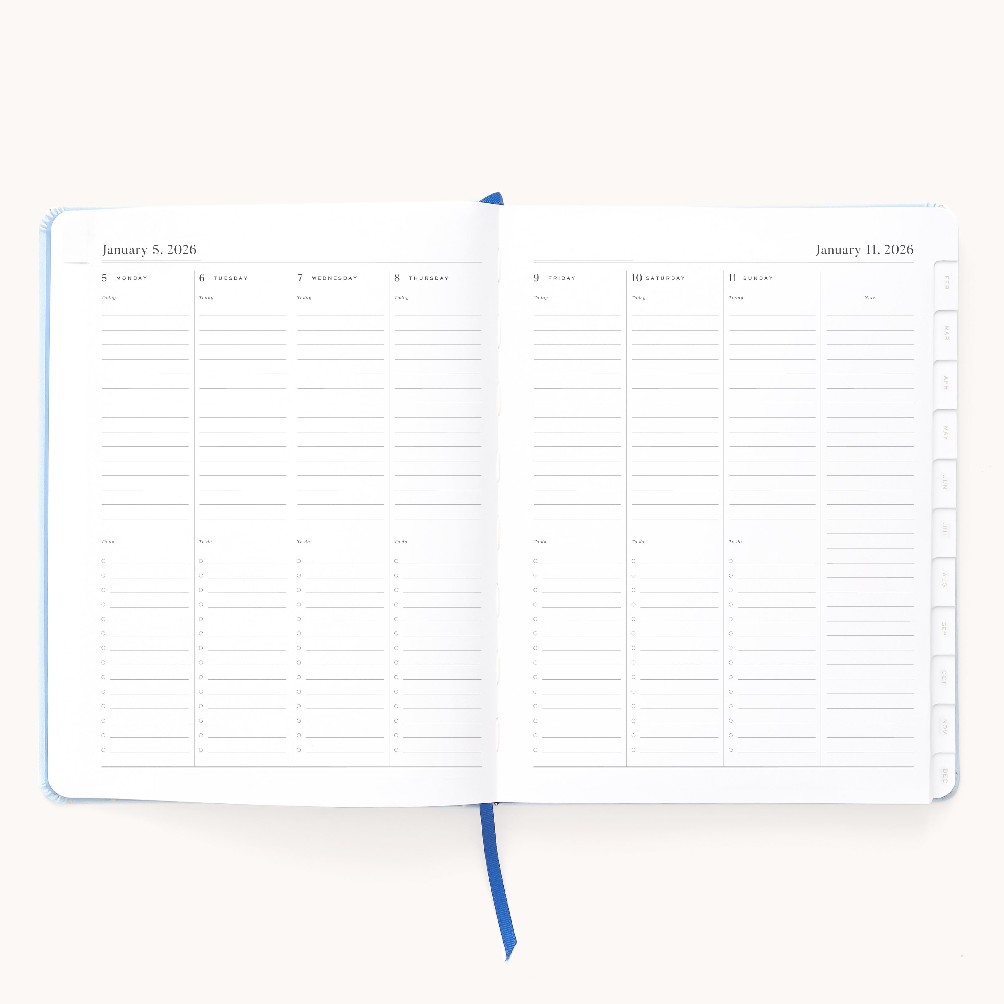 The Simplified 2026 Bookbound Weekly Dapperdesk Planner - Carolina Dot features a January 5–11, 2026 layout with daily columns, lined notes, right-edge tabs, a blue ribbon bookmark, and an elegant leatherette cover.