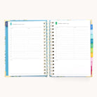 The 2025-2026 Spiral Daily Simplified Planner - Faraway Land by Simplified is open on a light background, showcasing gold foil details, dated sections for Wednesday and Thursday with hourly lines from 7 AM to 7 PM, colorful tabbed dividers on the right, and space for notes at the bottom.