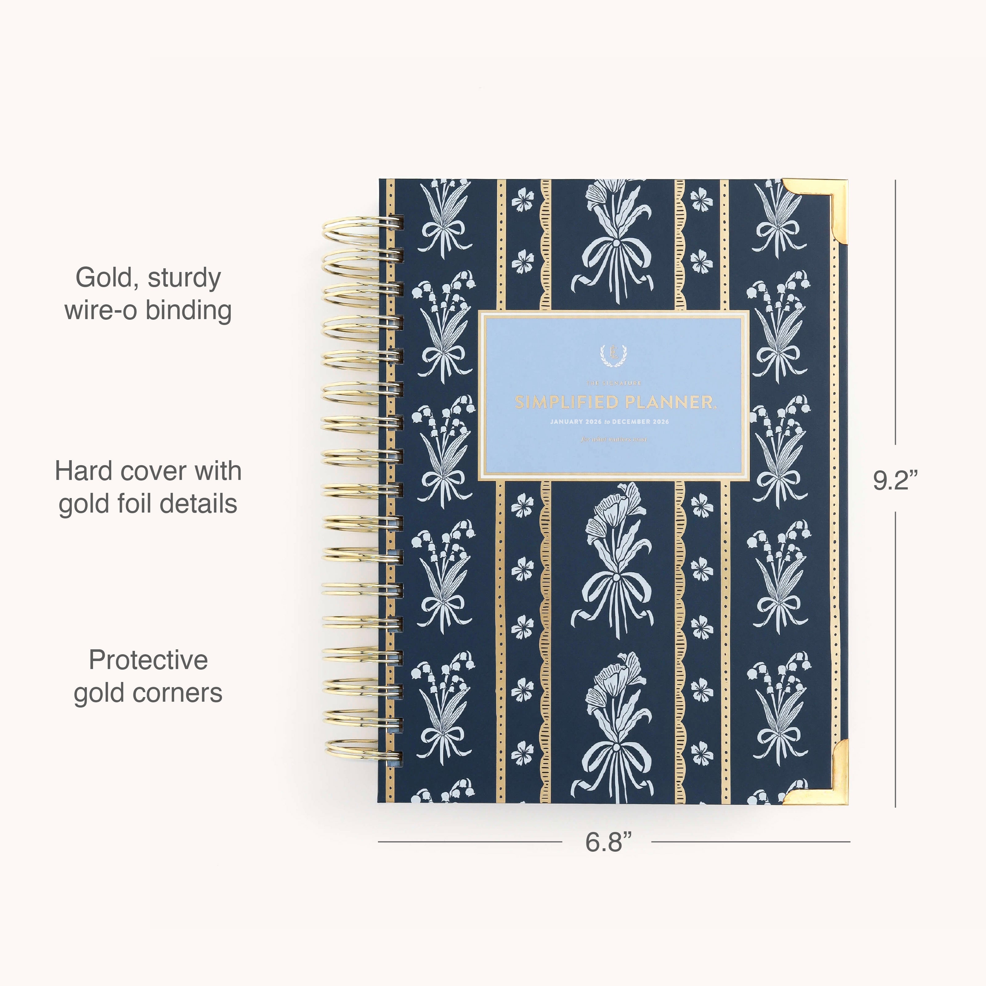 The Simplified 2026 Spiral Daily Simplified Planner – Poppy Posies features a navy blue hardcover with gold wire-o binding, gold foil floral accents, and protective corners. Size: 9.2 x 6.8.