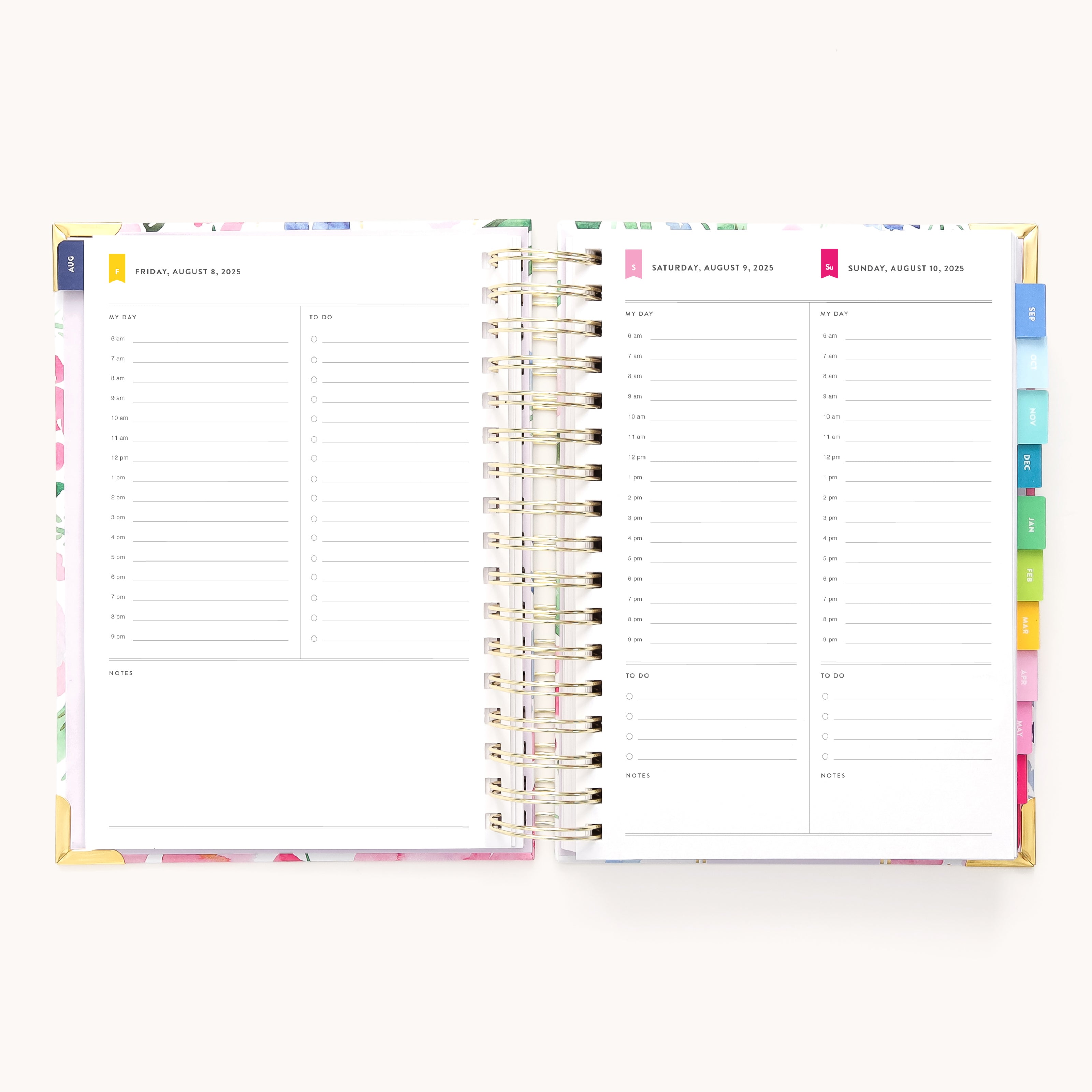 The 2025-2026 Spiral Daily Simplified Planner in Cottage Floral by Simplified is open, displaying two pages for Friday and Saturday with time slots from 6 AM to 9 PM. The planner features colorful tab dividers and elegant gold foil details.
