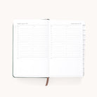 The Simplified 2025-2026 Evergreen Bookbound Daily Dapperdesk Planner shows Saturday and Sunday, August 8-9, 2025, with hourly slots from 7 AM to 9 PM and note space. It features a ribbon bookmark and tabbed sections on the right.
