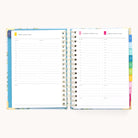 The 2025-2026 Spiral Daily Simplified Planner in the Faraway Land design is open, showing pages for August 7-9, 2023. Each page features a lined schedule with time slots and colorful tabbed dividers. Its cover boasts a blue floral pattern enhanced with elegant gold foil details.