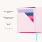 The 2025-2026 Bookbound Weekly Simplified Planner in Happy Stripe by Simplified features a back cover pocket with weekday-labeled sheets, blank spaces, and a blue ribbon bookmark on the right. Gold foil details enhance its elegant look, making it an ideal organized companion for your ideas.