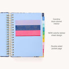 The 2025-2026 Spiral Daily Simplified Planner - Poppy Posies from Simplified gleams with its blue cover and gold foil details. Colorful index tabs line the right edge, while vibrant stickers enhance the pages, making organizing a joy in this elegantly designed planner.