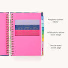The 2025-2026 Spiral Daily Simplified Planner - Rainbow Row from Simplified features vibrant pink pages, gold foil details, colorful index tabs on the right edge, a sheet of stickers with headings like Out of Office and Important, and exquisite gold accents on the corners.
