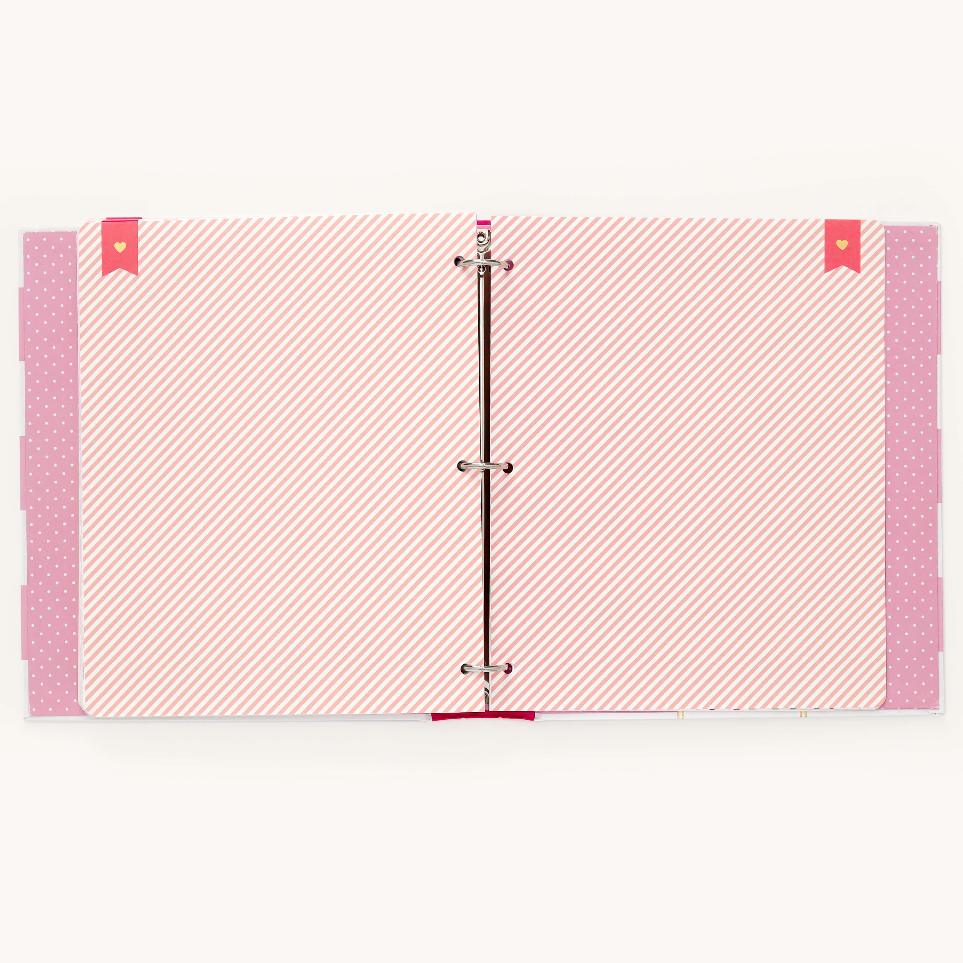 The Simplified Big Kid Book - Raspberry is a pink open binder with colorful pages, featuring striped and polka dot patterns. It has metal rings at the center and various colored tabs on the sides to capture a childs adventures.